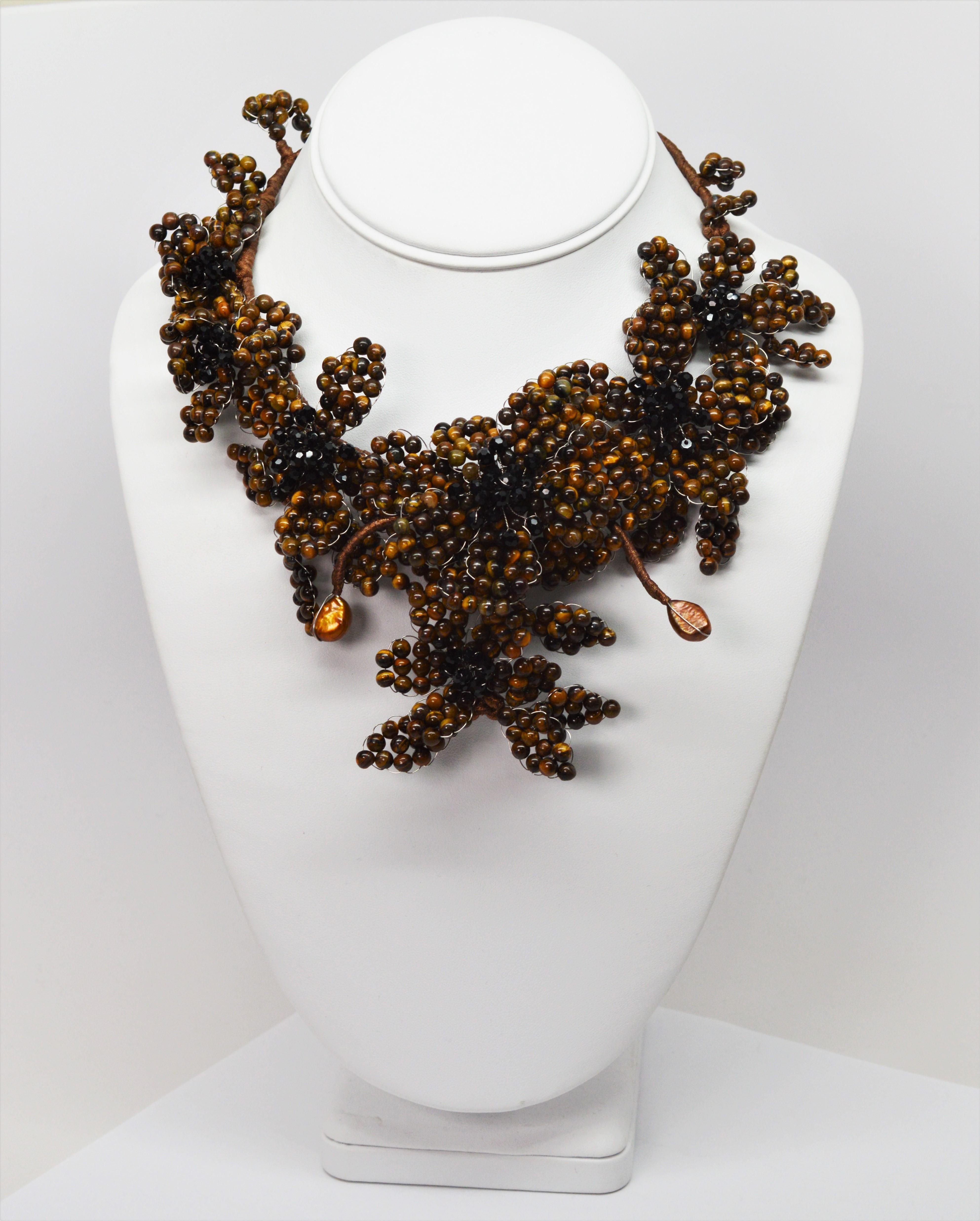 The golden tones of Tiger's Eye beads give this spectacular collar necklace it's rich look.  Cascading clusters of beaded petals weaved together in a vine like pattern make a dramatic statement. Handmade on a silk wrapped twenty two wire frame with