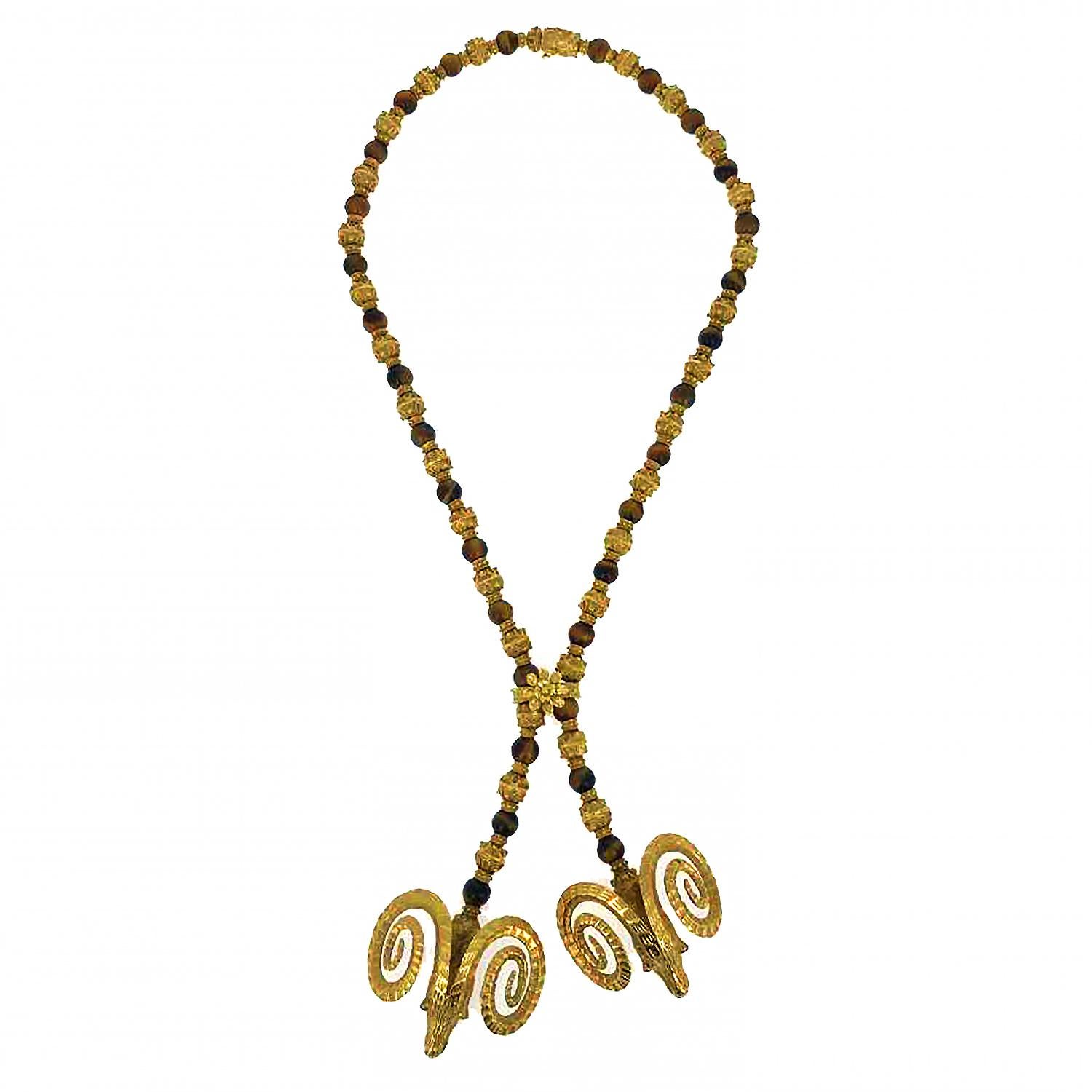 This vintage double-headed ram lariat necklace is comprised of alternating tiger's eye beads and textured 18 karat yellow gold beads with a twisted rope motif. The lariat clasp is fixed. The necklace is accompanied by a double-headed hinged ram