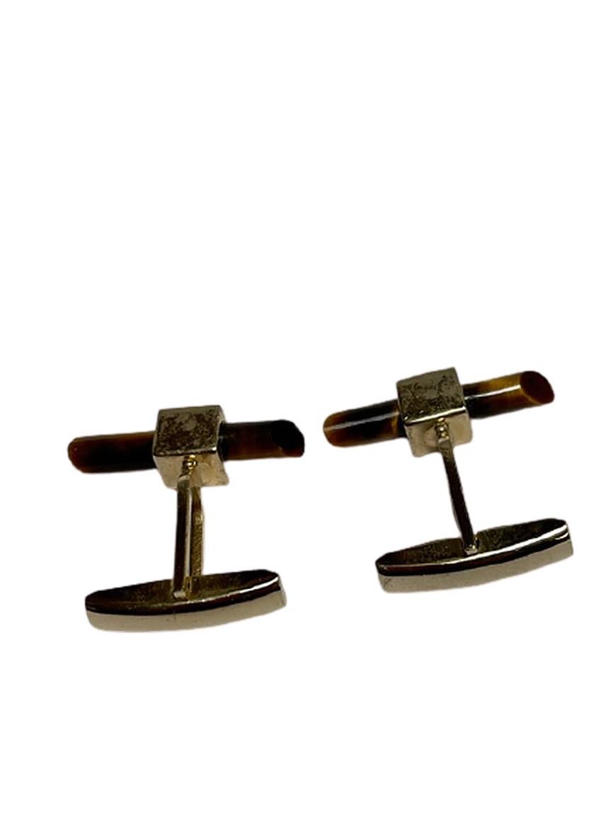 These gold cufflinks feature tiger's eye gemstones, which have been formed into power rods. The gemstones have a beautiful gold and brown sheen to them, even in low light situations. However, when the light is right, they roar with excitement.