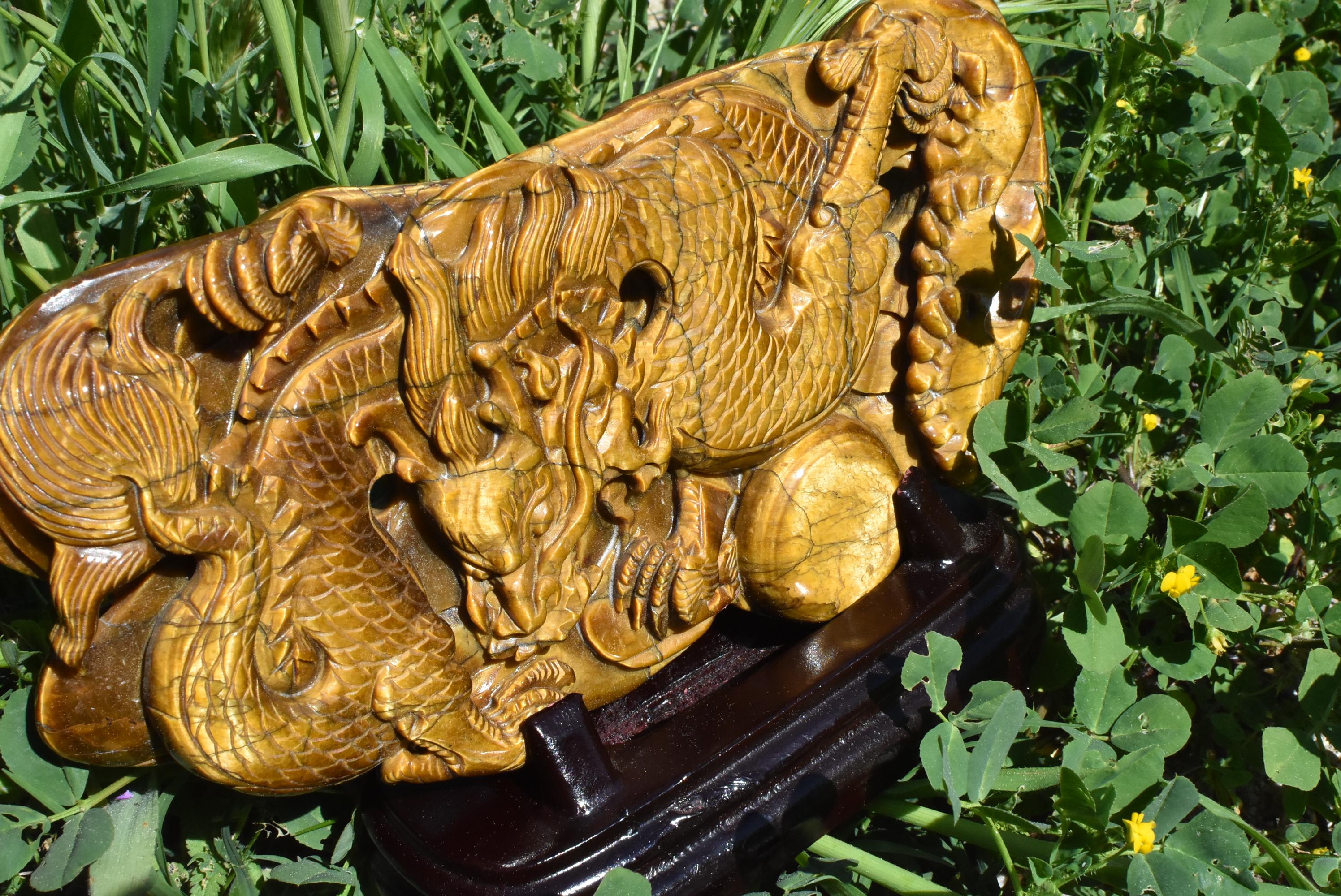 A stunning all natural genuine tiger's eye sculpture depicting a dragon chasing a ball. The sculpture is made with a whole slab of natural Tiger's Eye with fantastic iridescence. Fine carvings make the dragon come to life. Solid wood custom stand.