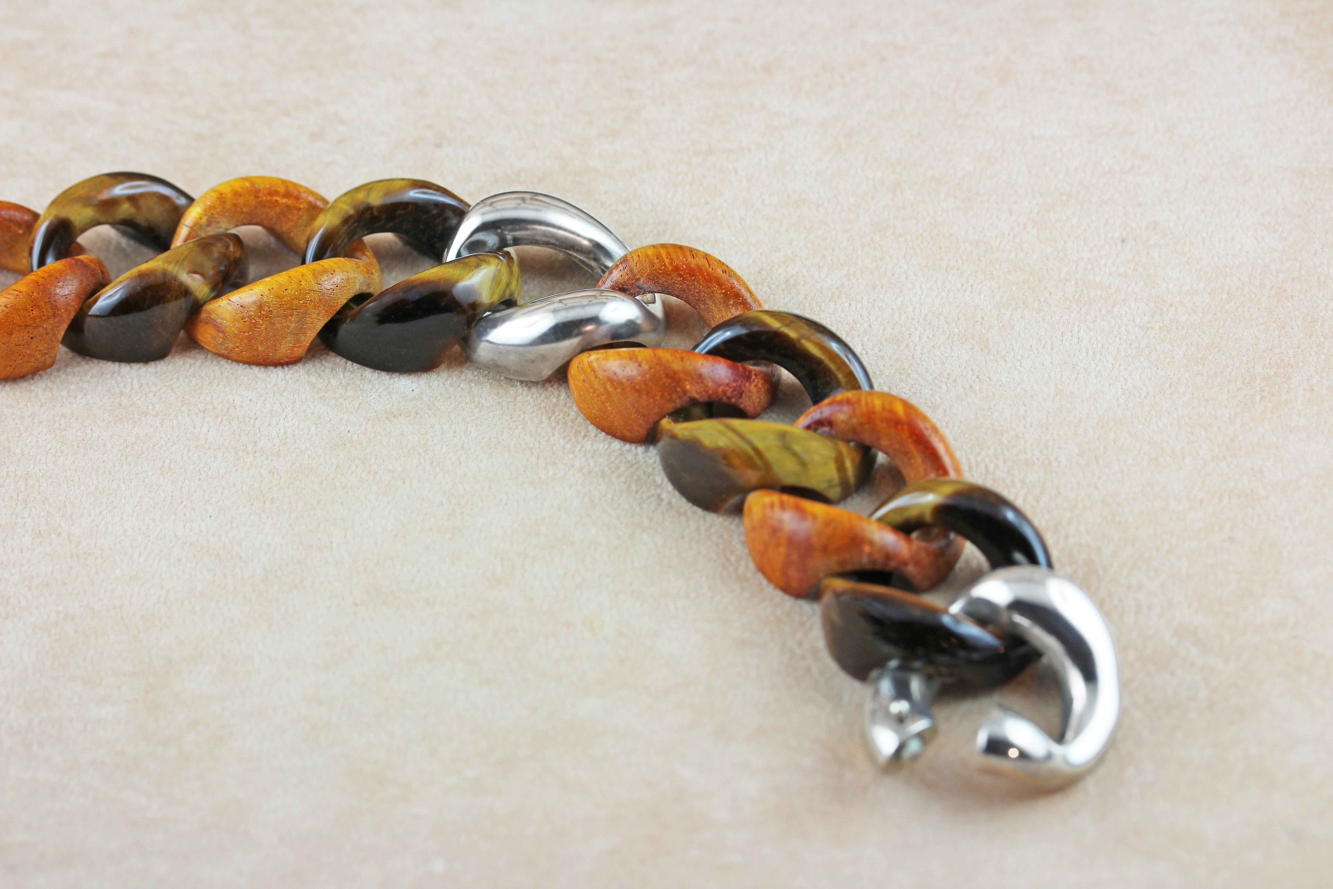 In this elegant groumette bracelet orange wooden rings are alternate with links made in tiger eye's creating a striking combinations of textures, finishes, and colors, mixing sophistication and a contemporary allure.
The clasp and one link in the