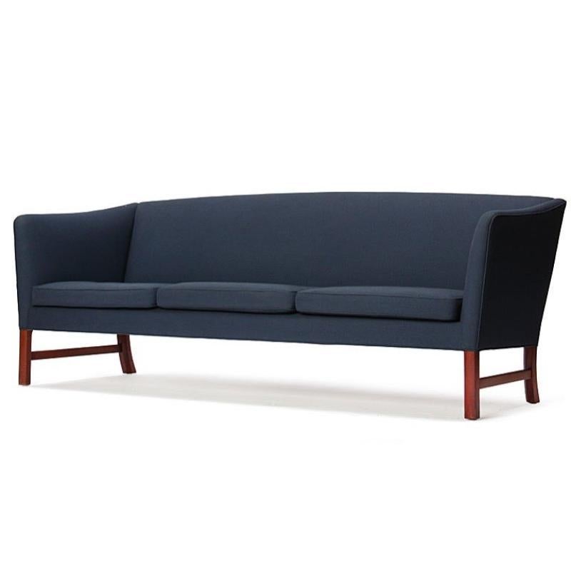 A tight back sofa with sloping arms, retaining the original blue upholstery on Cuban mahogany legs.