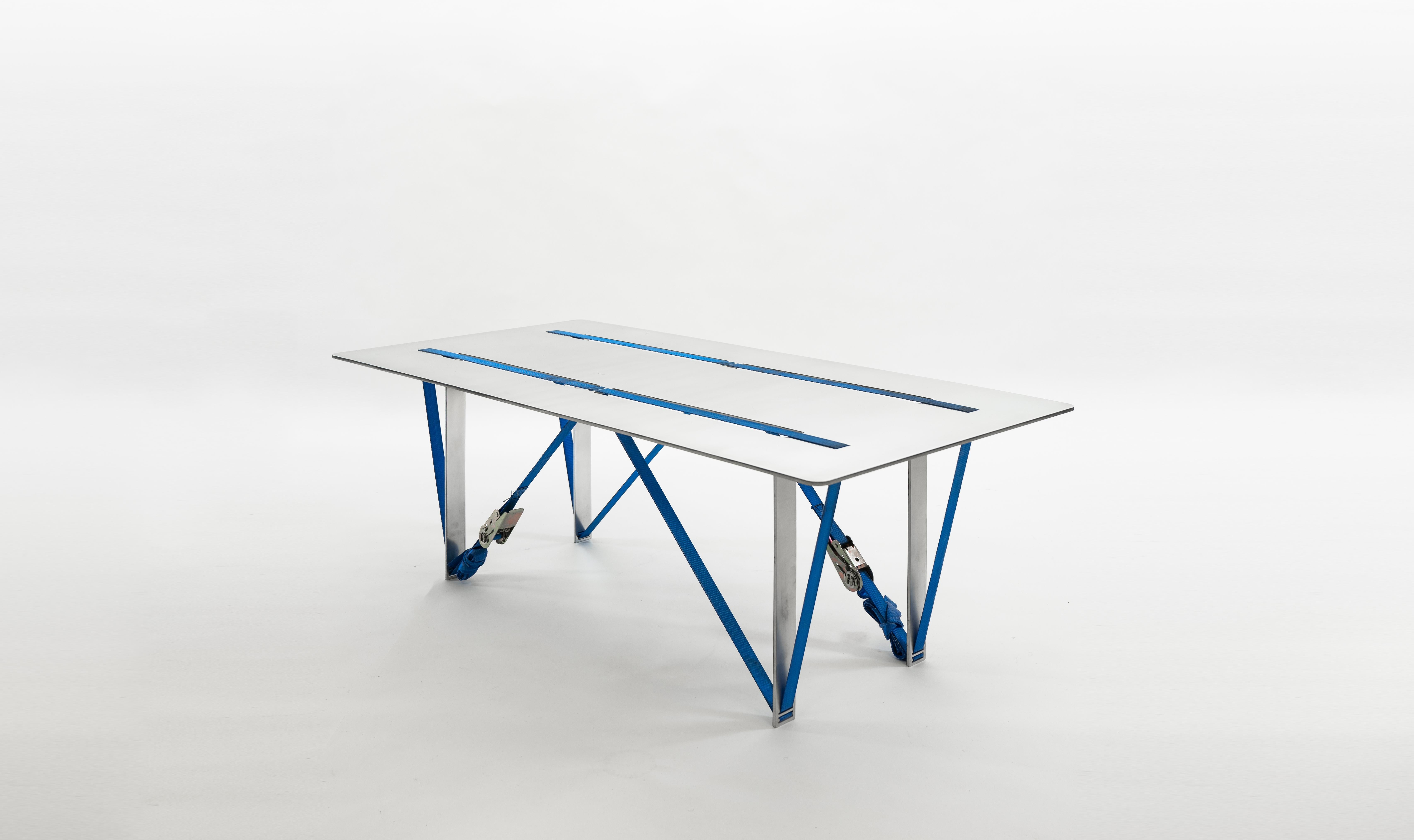 The Tighten table is range of household, display and exhibition tables each created from a single sheet of hand-polished, recycled aluminium, manually bent and tensioned with ratchet straps. The series originates as a study into manufacturing a
