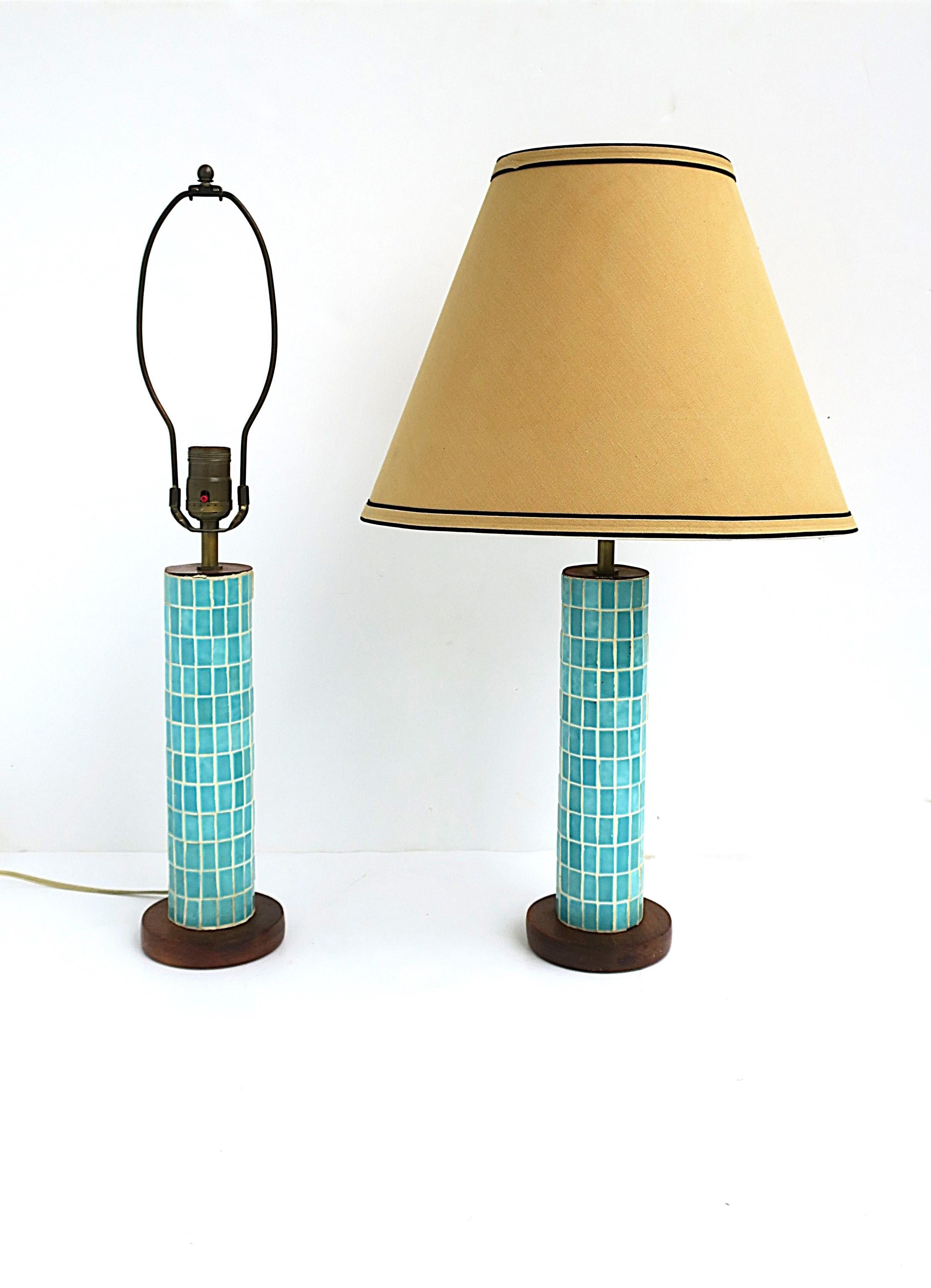 A beautiful pair of turquoise blue tile mosaic table lamps, Midcentury Modern period, circa mid-20th century. Lamps have a turquoise blue mosaic tile cylindrical center, wood base and top area, and original brass hardware with beautiful patina.