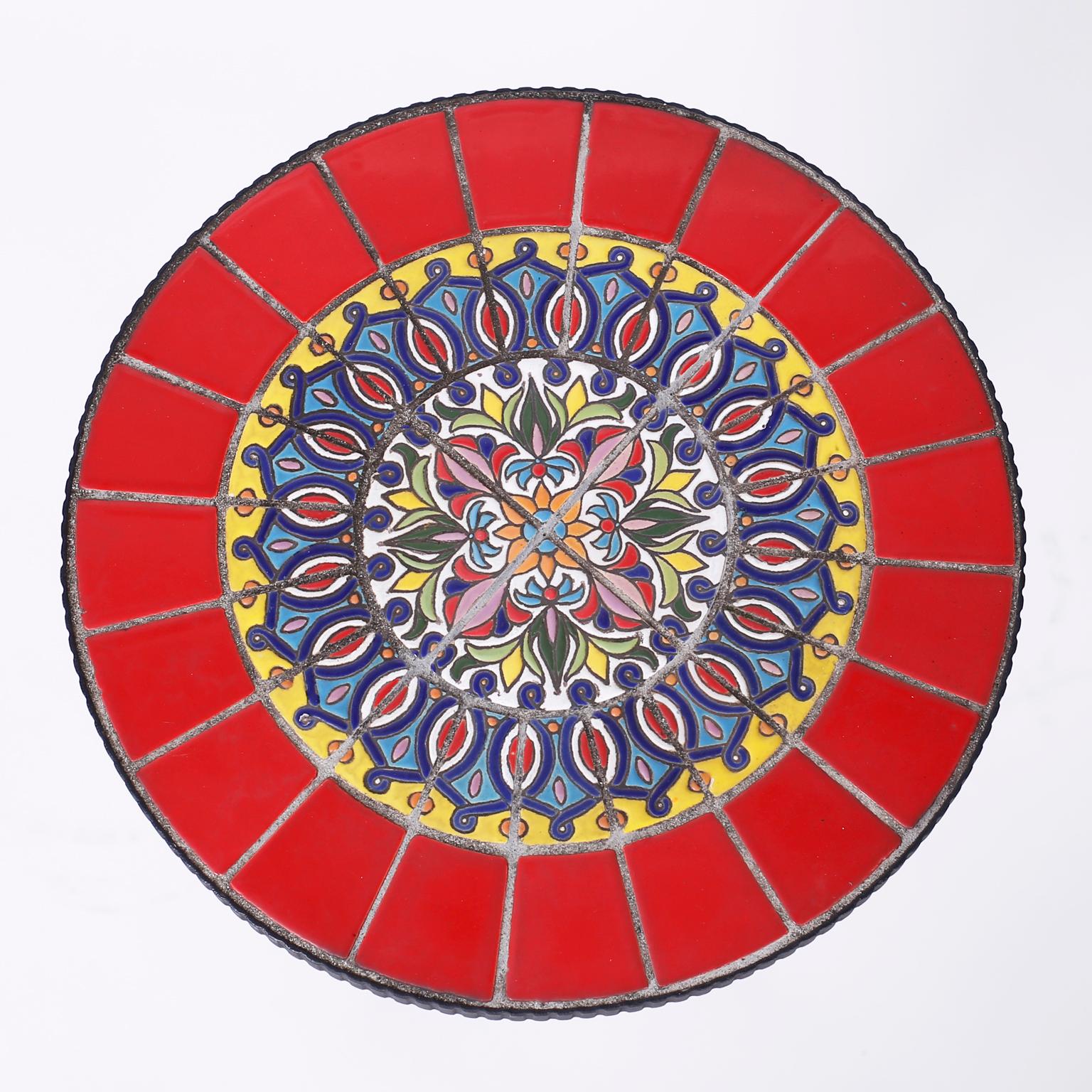 Midcentury tabouret or table with an iron base and a bold colorful kaleidoscopic tile top with floral and geometric designs.