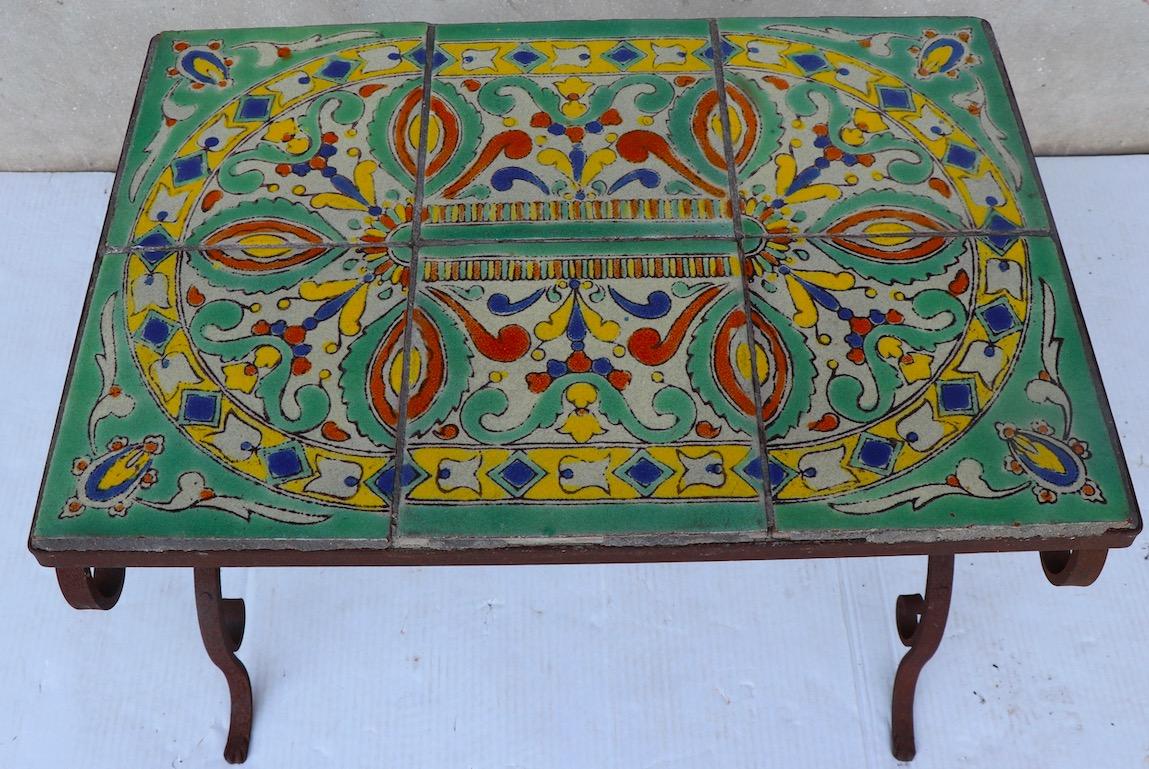 Chic wrought iron base, tile top garden or patio table, with six square tiles forming the rectangular top. The tiles are reminiscent of Catalina Pottery, the table is circa 1920s-1930s. Some of the grout which holds the tiles in place is missing,
