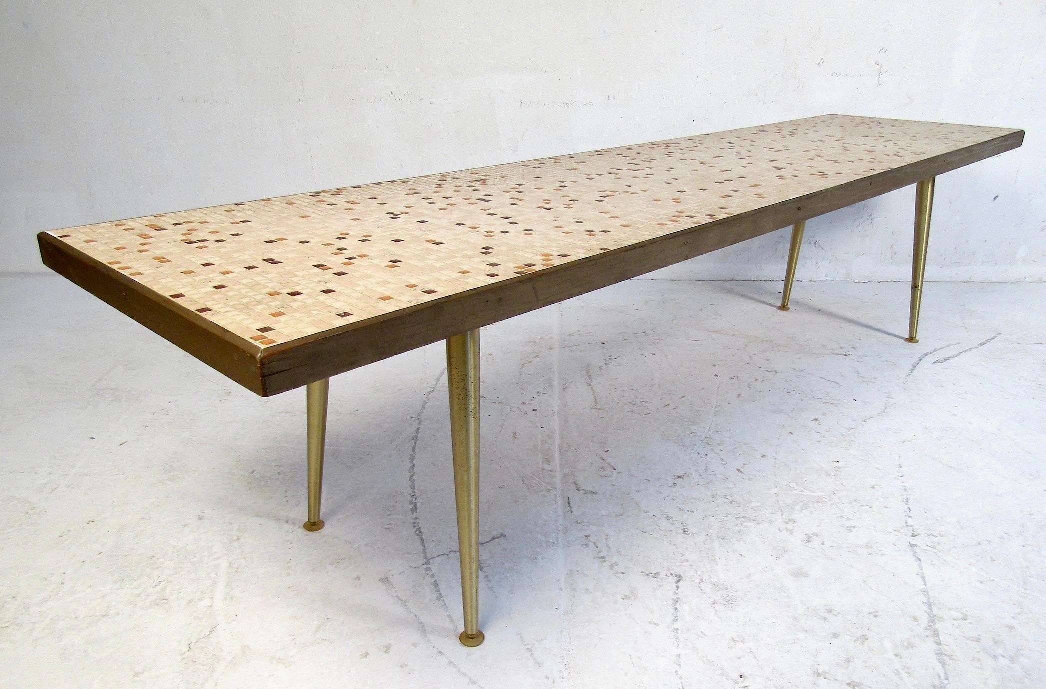 Intéressante table basse à plateau en carreaux de faïence avec garniture en bois. La table est soutenue par un ensemble de pieds en laiton évasés. Une étonnante série de petits carreaux confère au plateau de table un aspect tout à fait unique.