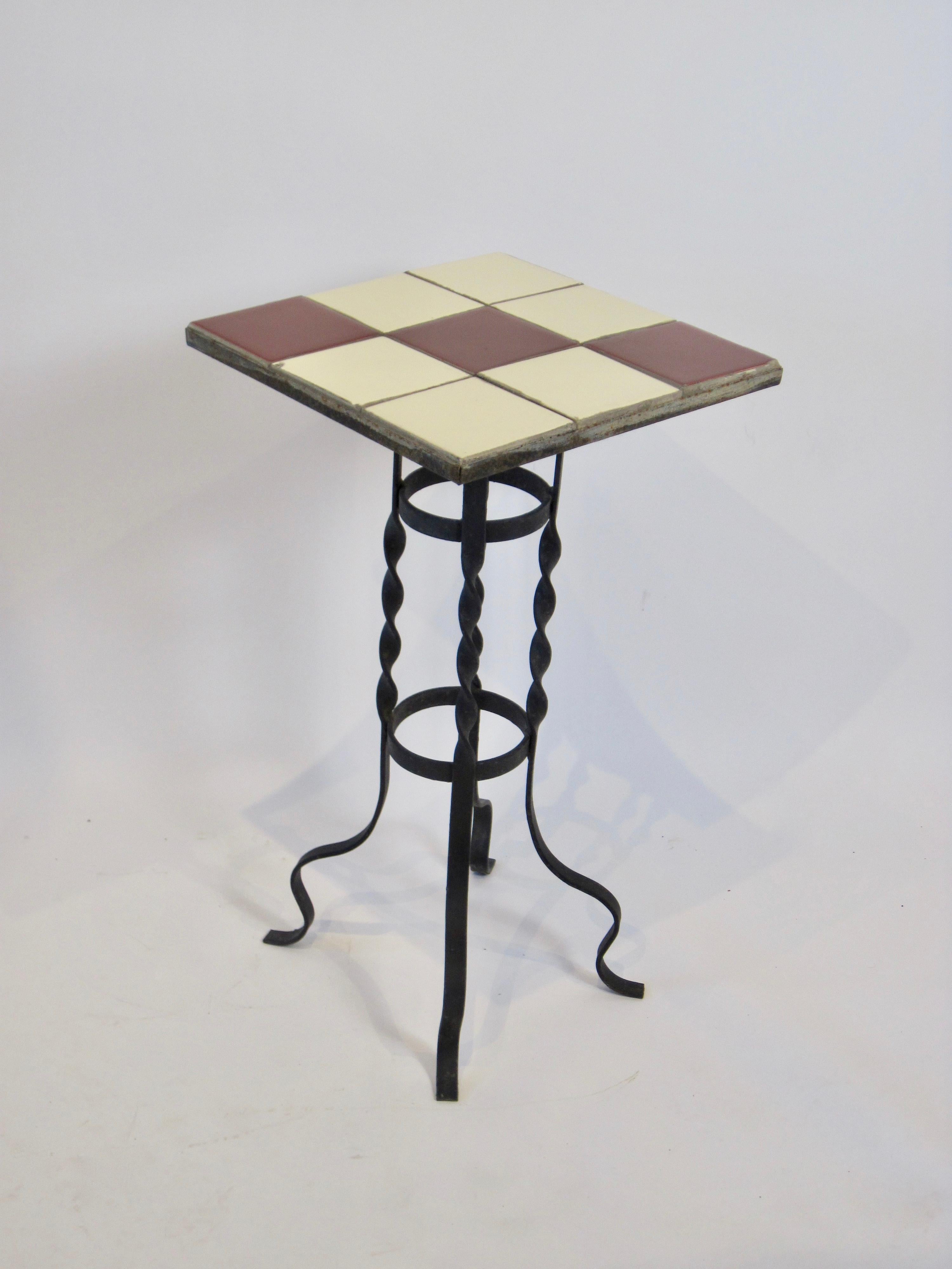 A 1950s red and cream tile-top plant stand table with twisted wrought iron base. Suitable for inside or out.