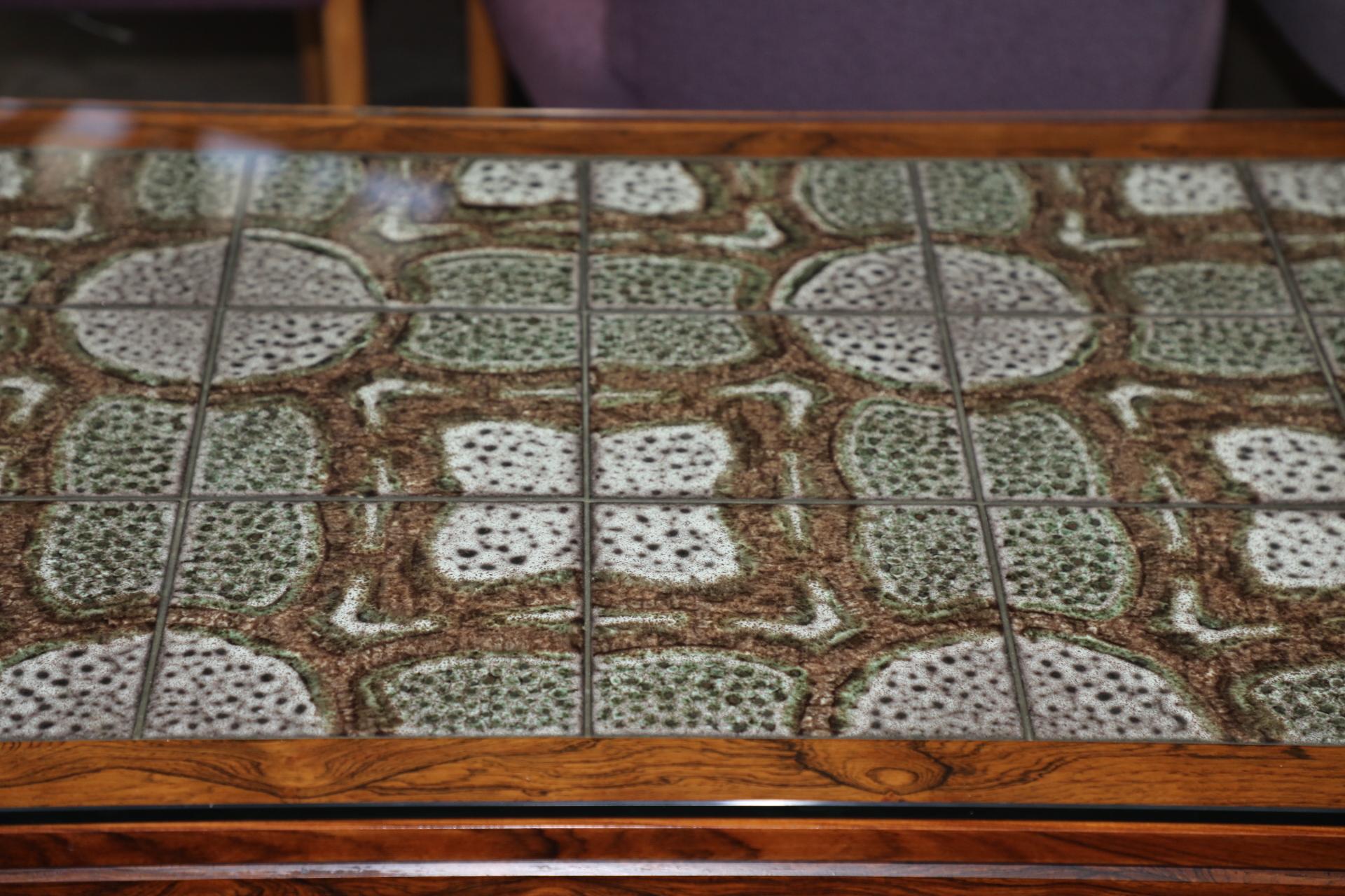 A nice vintage cocktail coffee table with a tile top. The top features protective glass that is not original. This table is vintage. There is a small ding to one side, and some age appropriate wear and marks.