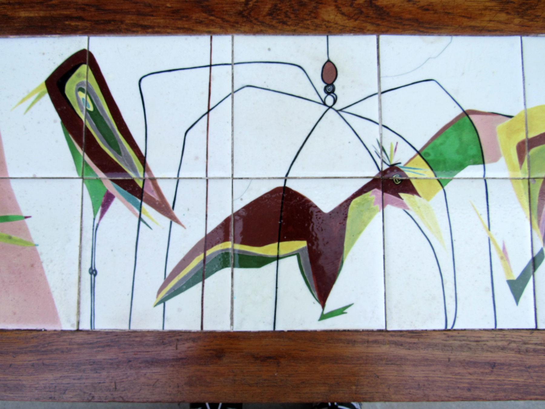In the midcentury manner of Aldo Londi colorful birds on long skinny legs delight and charm in this hand painted tile table created from tiles taken from a wall in Italy in the 1960s. Mahogany frame and wrought iron legs.