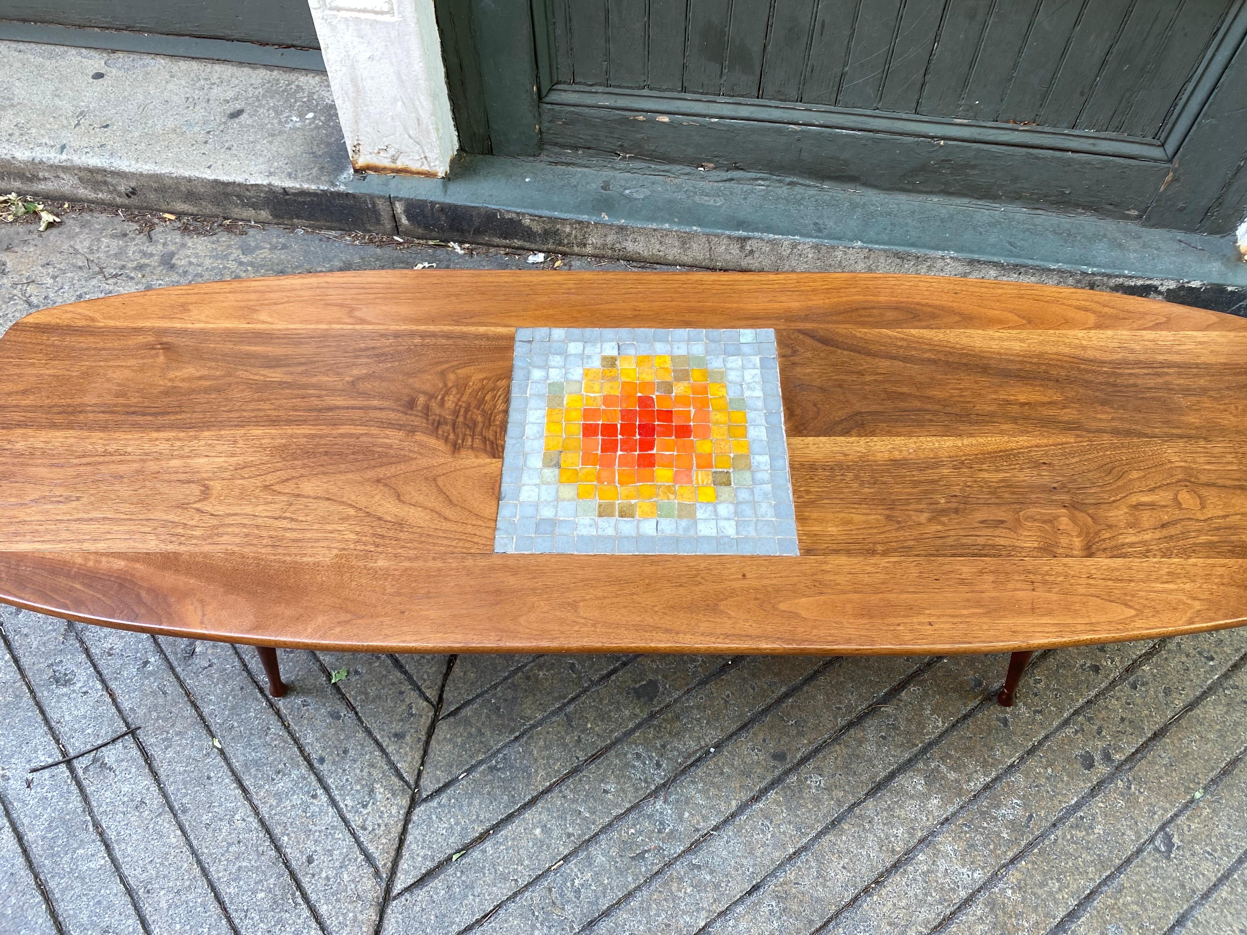 Walnut Boat Shaped Coffee Table with italian glass tiles in the center. Nice burst of color and texture. Very nice smaller scale. Legs unscrew for easy transporting!