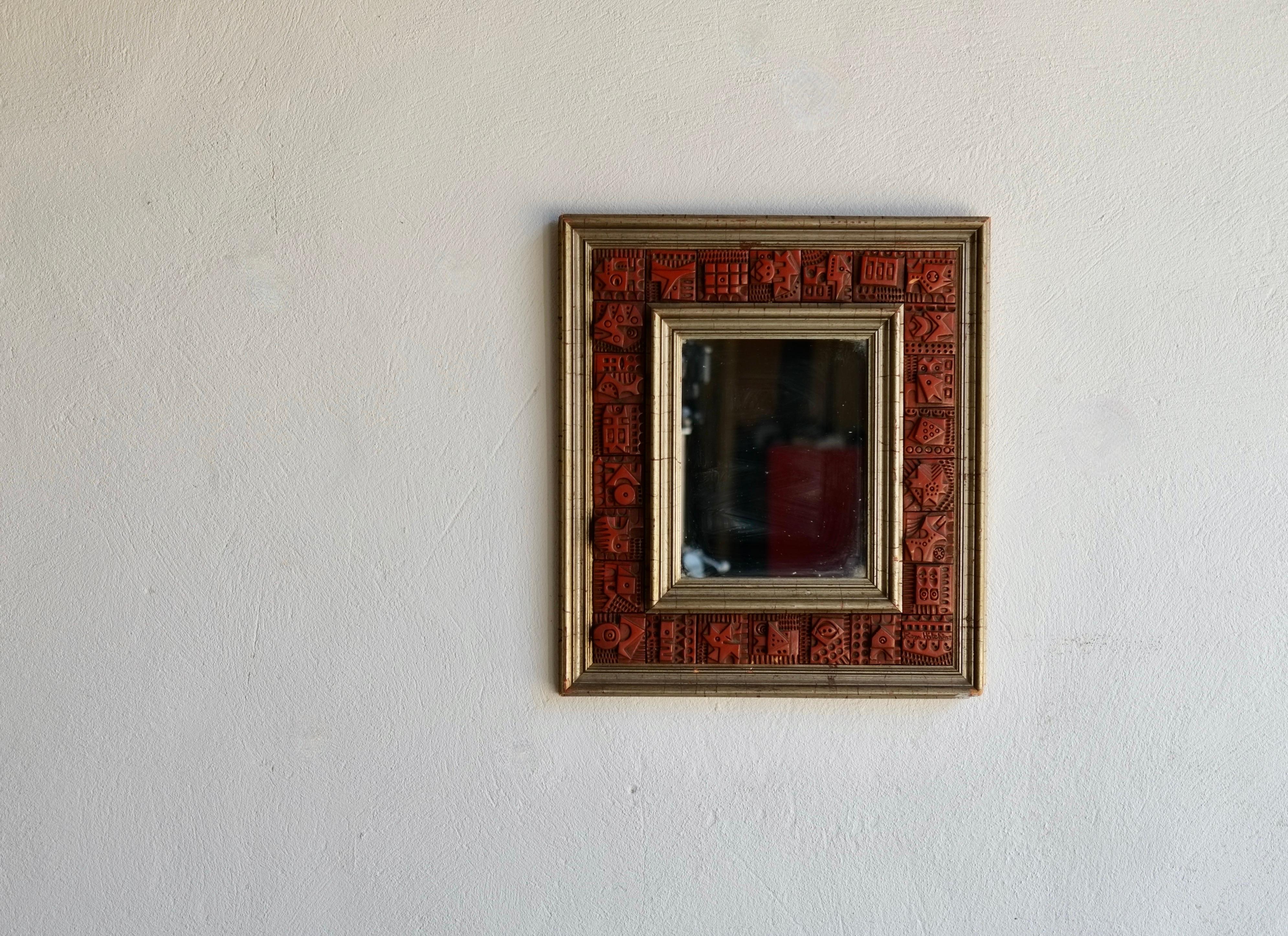 A signed wood and terracotta tile wall mirror by renowned Hackney artist Ron Hitchins (1926-2019) circa 1960's.