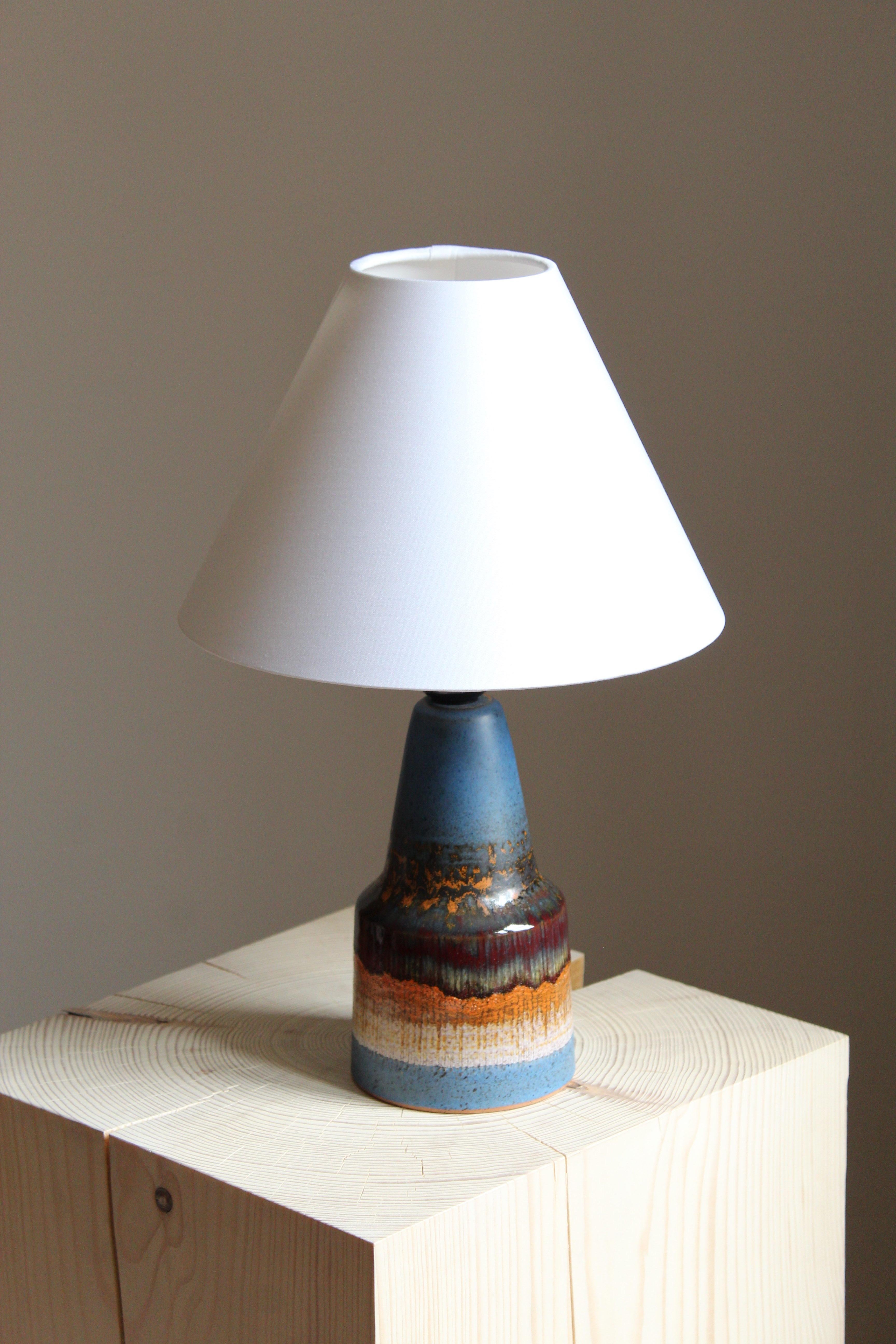 An artisticly glazed stoneware table lamp. By Tilgmans Keramik, 1950s. 

Dimensions noted are excluding lampshade.  Lampshade is not included in the purchase. Made to be fitted with lightbulb-clip.

Glaze features blue-orange-red-green-white