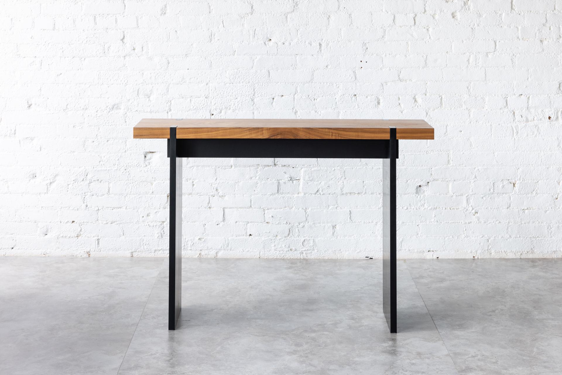 The Tillikum Black Console in black walnut features a Black Walnut solid wood top set on a matte black frame and legs. The minimalist design by Kirk Van Ludwig combines these elements to create a modern entrance console. 

Perfect attention-grabbing