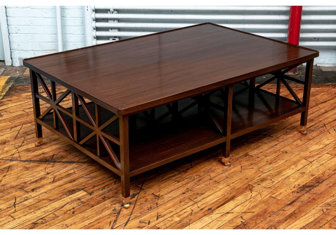 A particularly refined and airy design in a larger cocktail table. With a rectangular top made in planks with a carved lip. With three openwork supports of criss-cross bars on the ends and one across the middle. The lower tier raised on square legs