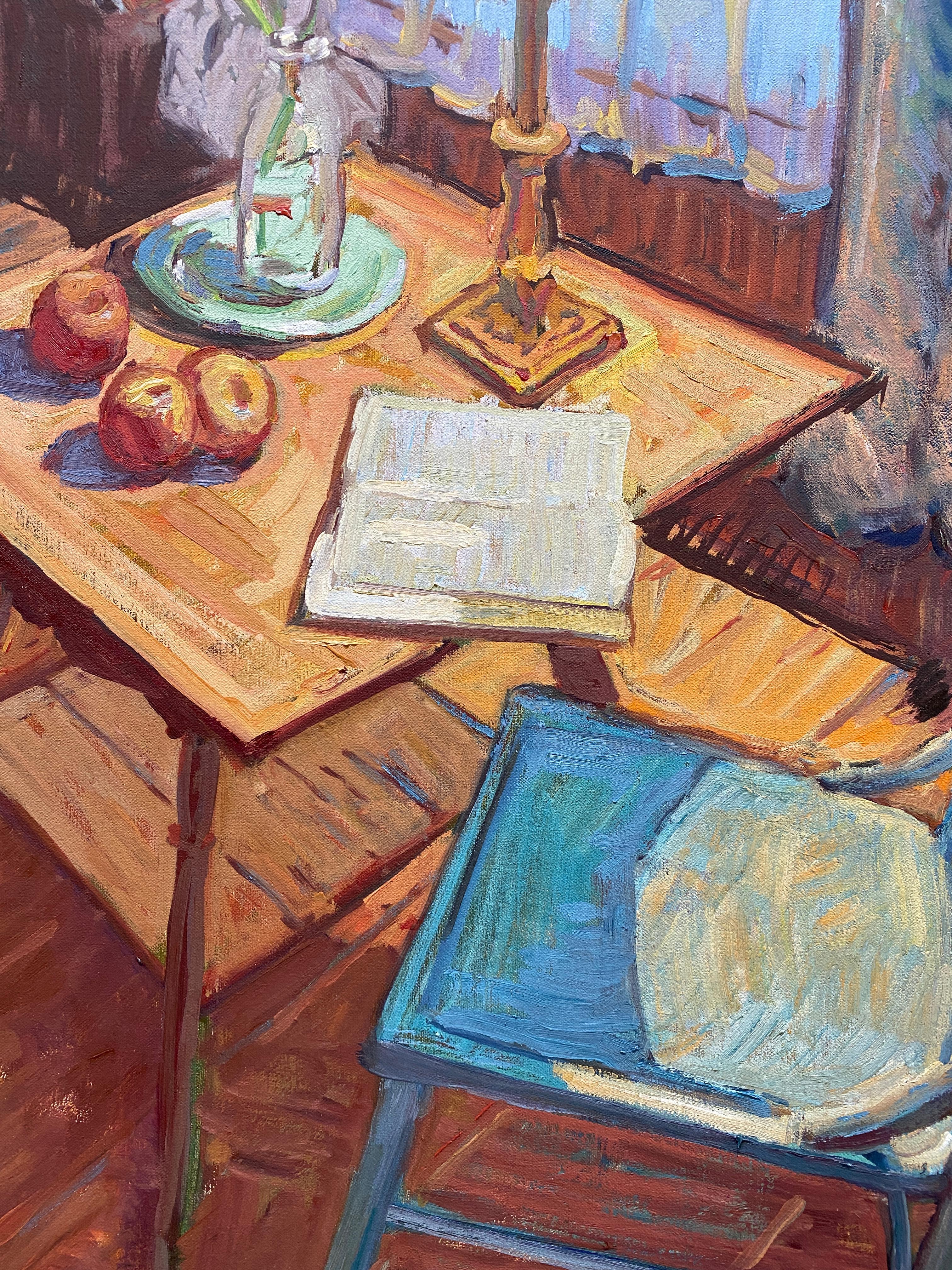 An oil painting of an interior soaked in hues of blue. A traditional wooden chair is pulled out from a small wooden table, where an open book, a vase of Persian Buttercups, a group of apples, and a stylish bell lamp are situated. The background is