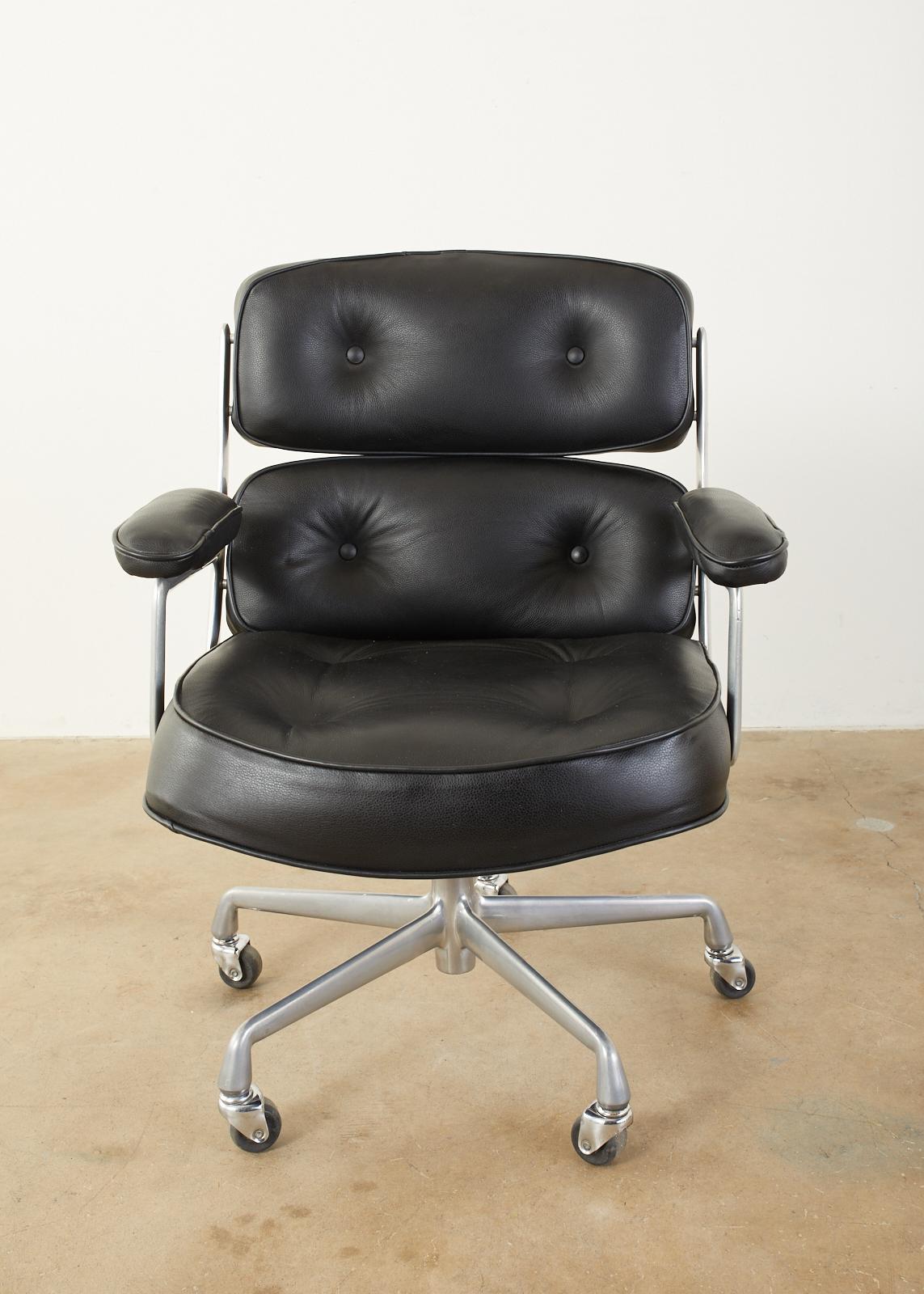 Handsome Time Life executive desk chair designed by Charles and Ray Eames for Herman Miller. Features an iconic aluminum frame with thick, padded, and tufted black leather upholstery. Supported by a 5 leg base ending with casters. The arm measures