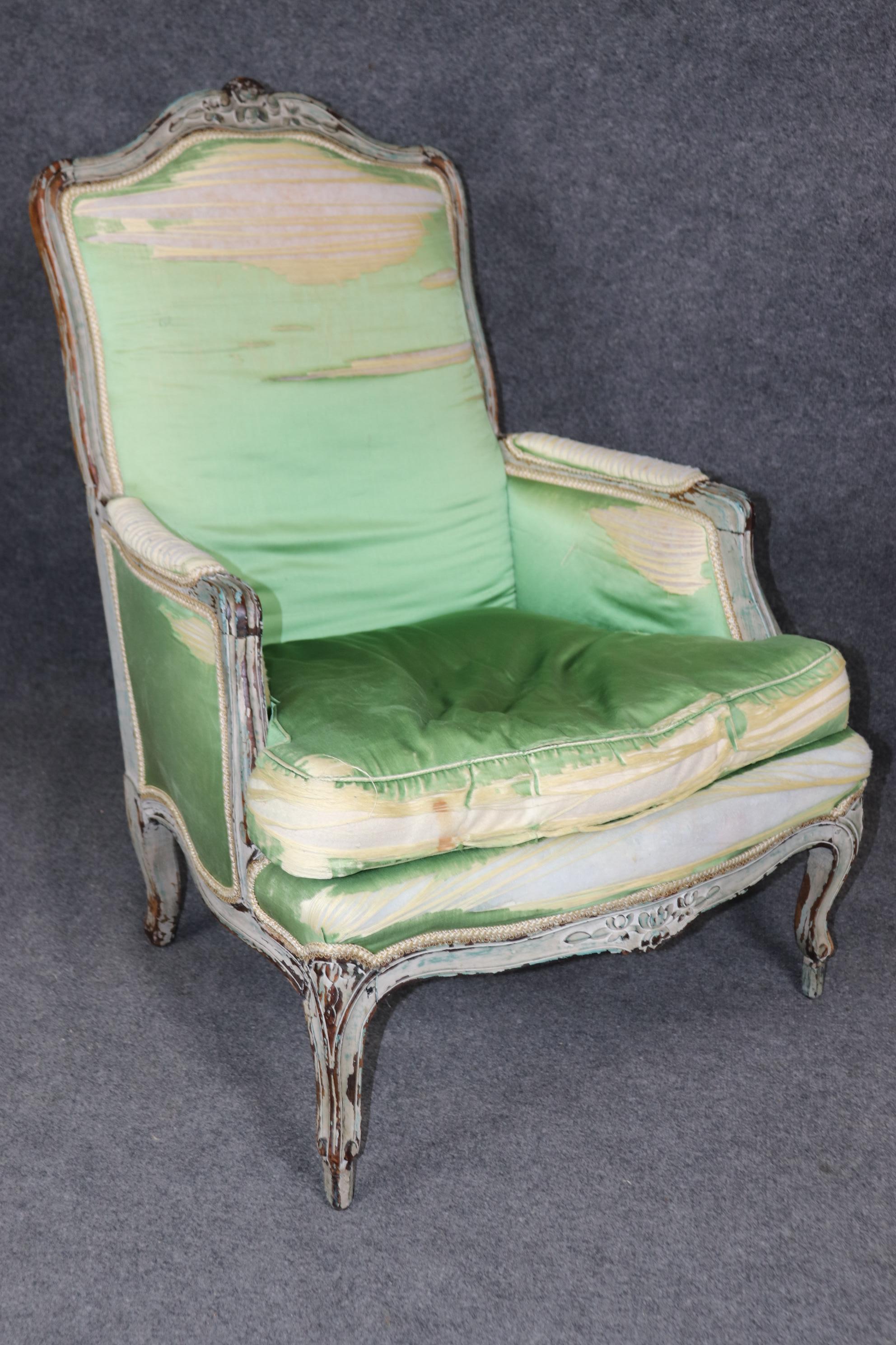 This is a fantastic and rare pair of period 1780s era French Louis XV bergere chairs. The chairs are in their original time-worn distressed painted finish revealing numerous layers of colors and old if not entirely original upholstery with goose