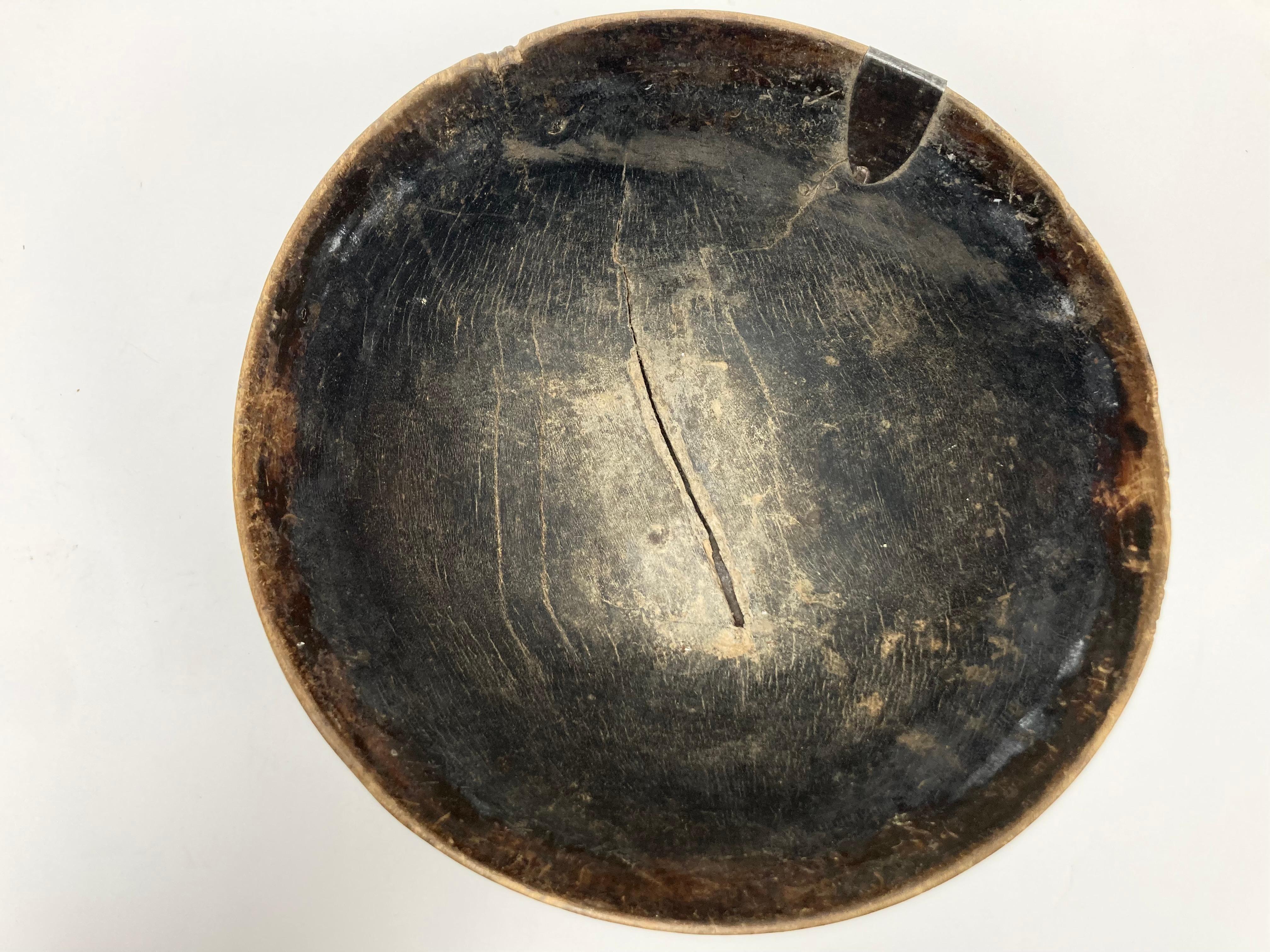 Una ciotola artigianale e utilitaria proveniente dall'Africa. La ciotola è di buone dimensioni e ha uno stile fine e naturale, con una profonda tonalità dell'età e riparazioni al bordo e alla base con chiodi di metallo a testa quadrata. Ben