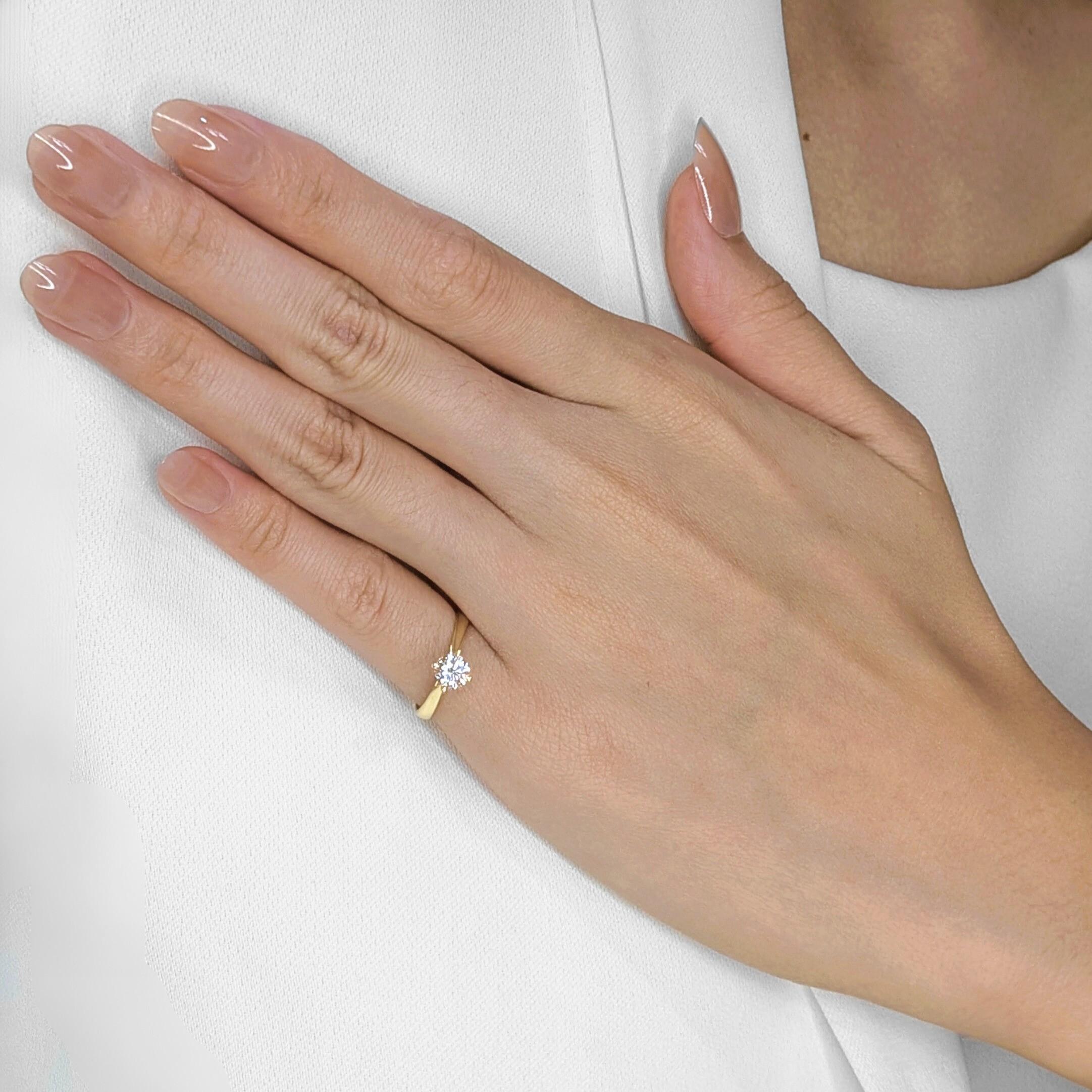 Eleg : l'éclat chaleureux de l'or jaune 18 carats enveloppe un brillant diamant rond de 0,5 carat, symbole intemporel d'élégance. Cette bague solitaire d'occasion, au design classique, permet à la beauté naturelle du diamant d'occuper le devant de