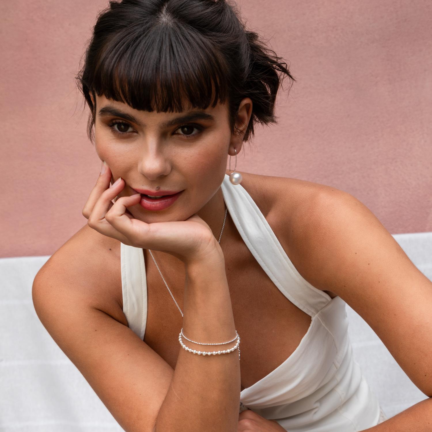 This stylish pair of sterling silver drop earrings feature beautiful 14mm white freshwater pearls. Each pearl is set onto a hammered disc with long, elegant ear wires. Made in our London studio, the timeless simplicity of this design means the