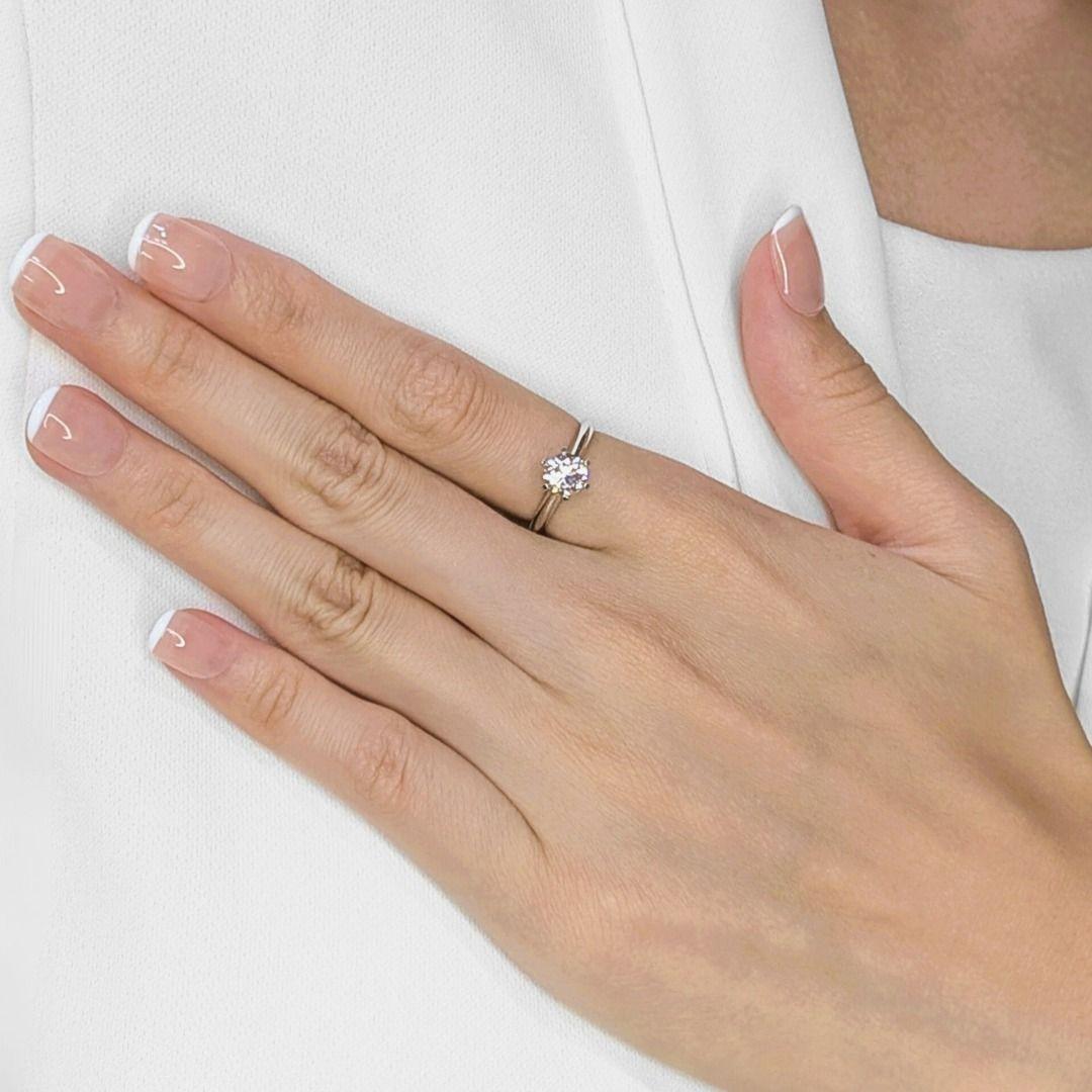 Presenting a brand new and unworn solitaire ring that embodies timeless elegance. A stunning 1-carat natural diamond, cut in a classic round brilliant shape, takes center stage. The diamond's near-colorless J grade offers a lovely warmth, while its