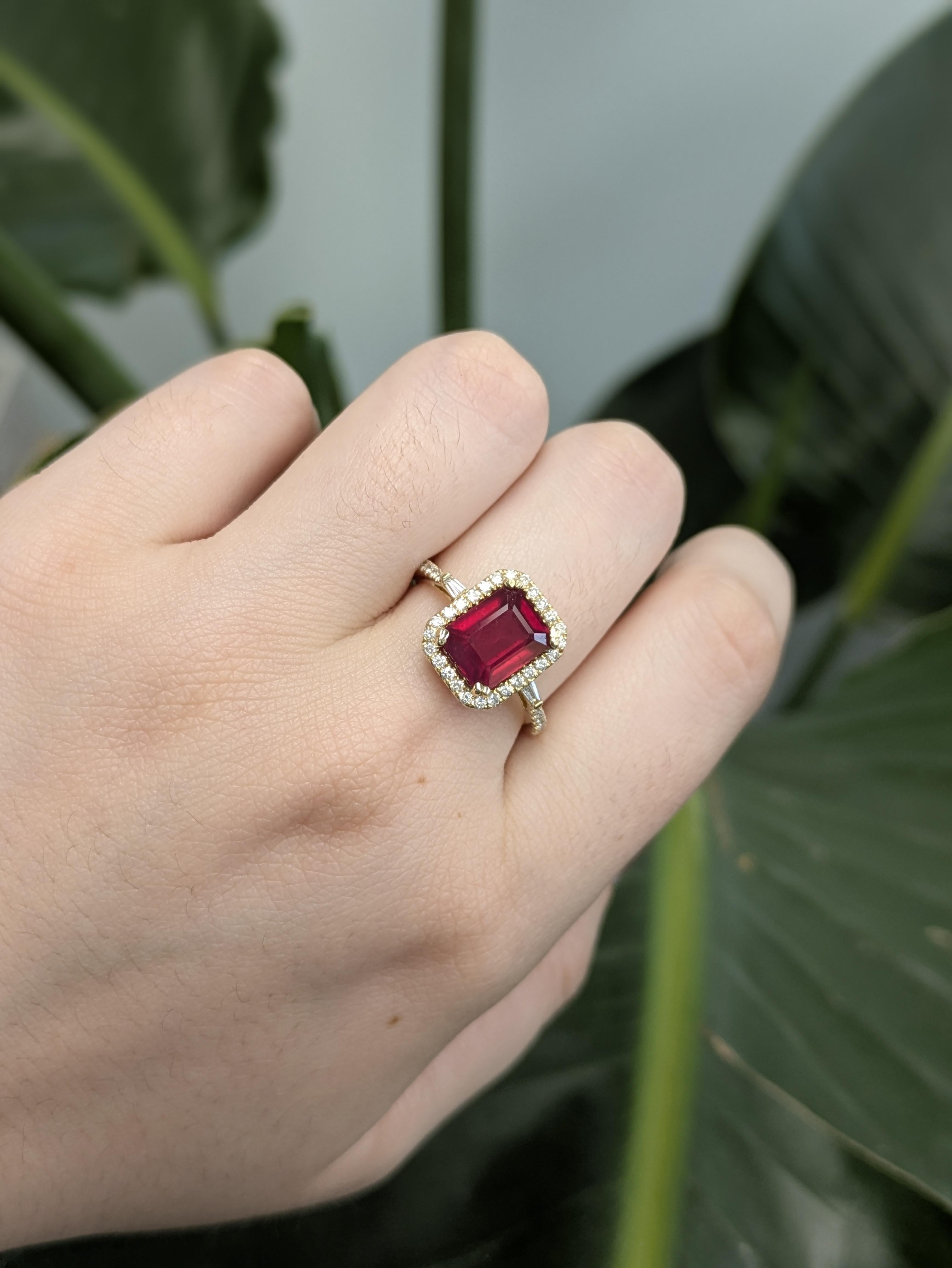 Dieser 2,6-karätige Rubinring im Smaragdschliff zeichnet sich durch einen sattroten Mittelstein aus, der von runden und baguettierten Diamanten in einem funkelnden Halo akzentuiert wird. Dieser Ring aus 14-karätigem Gelbgold verbindet klassischen