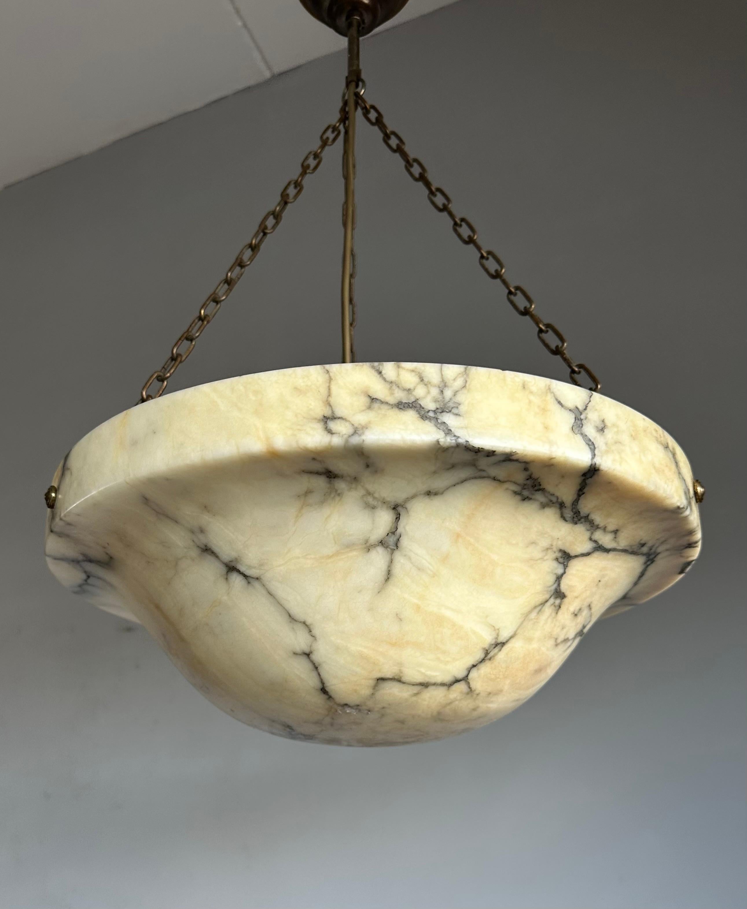 Timeless masterpiece and superb condition alabaster light fixture with thunderstroke-like black veins.

Imagine a sultry evening in the 1920s as the warm glow of an exquisite alabaster pendant light fills the room. The brass details shimmer in the