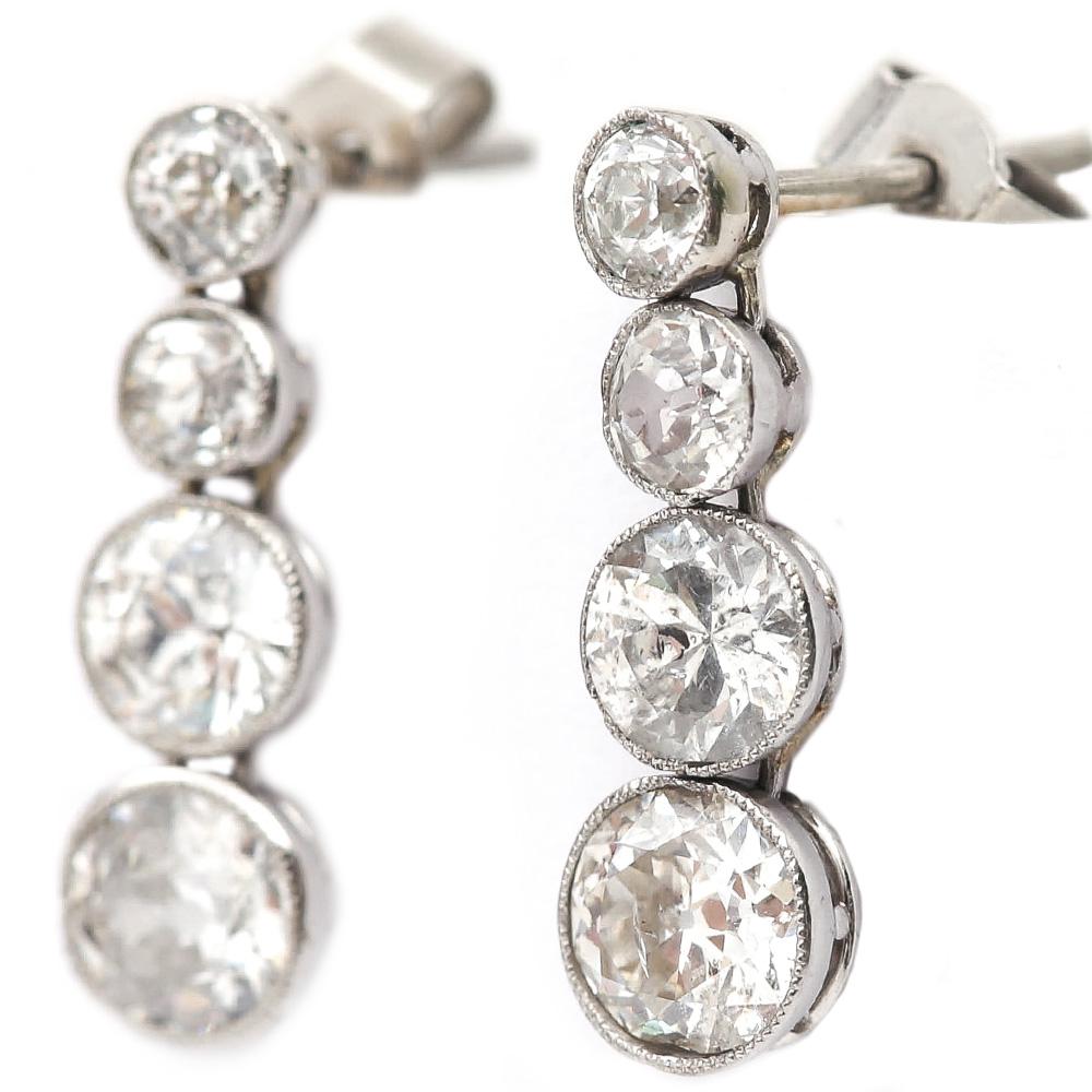 A super pair of original Art Deco platinum diamond drop earrings. Each are made up of four Old Mine cut diamonds in Roman settings with a millegrain edge which was typical of this period 1920-1930. The Old Mine cut diamonds are graduated from the