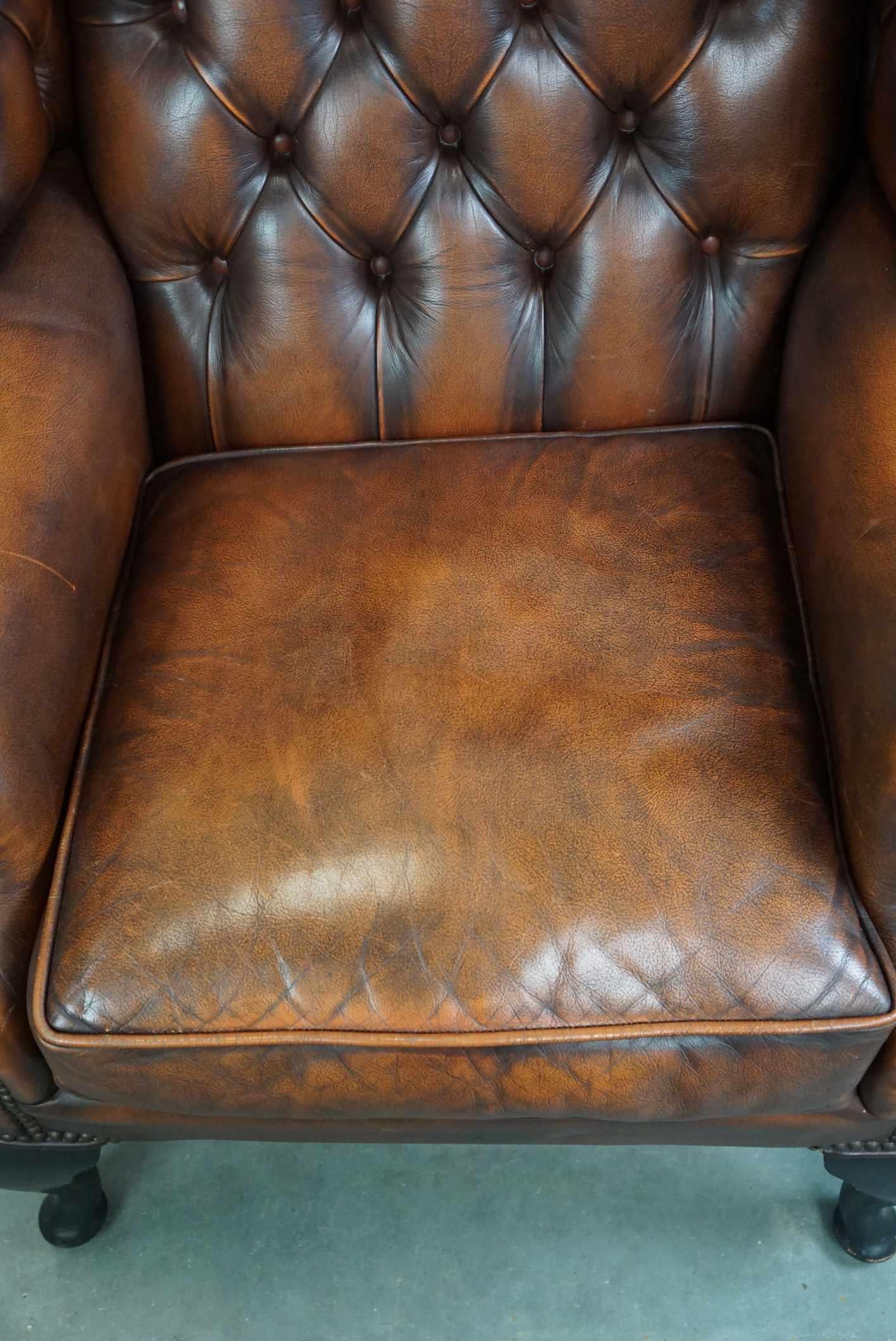 Cowhide Timeless cognac-colored English cowhide Chesterfield wingback armchair in good c For Sale