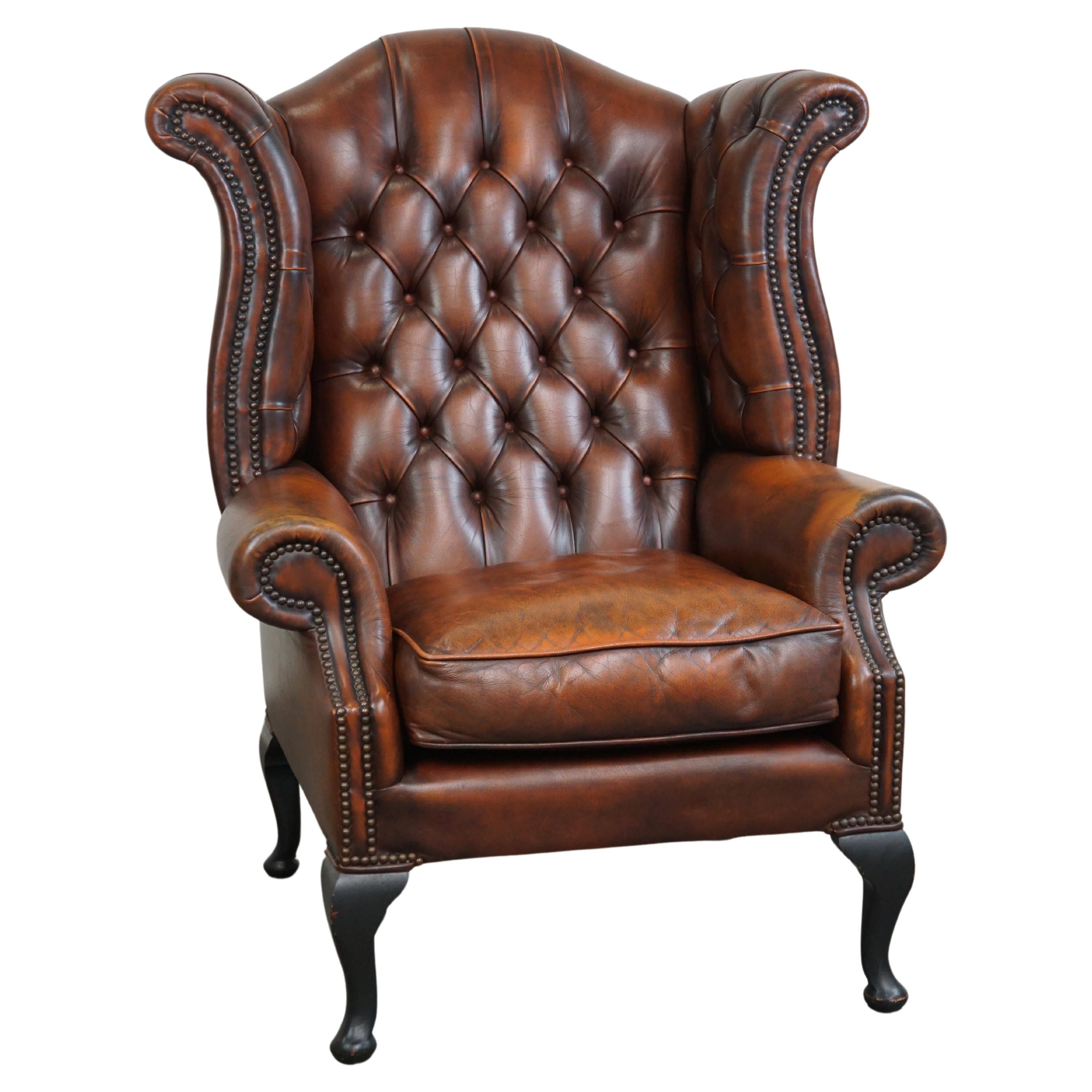 Timeless cognac-colored English cowhide Chesterfield wingback armchair in good c For Sale