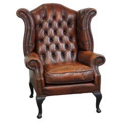 Timeless English cowhide Chesterfield wingback armchair in good c, cognac colour.