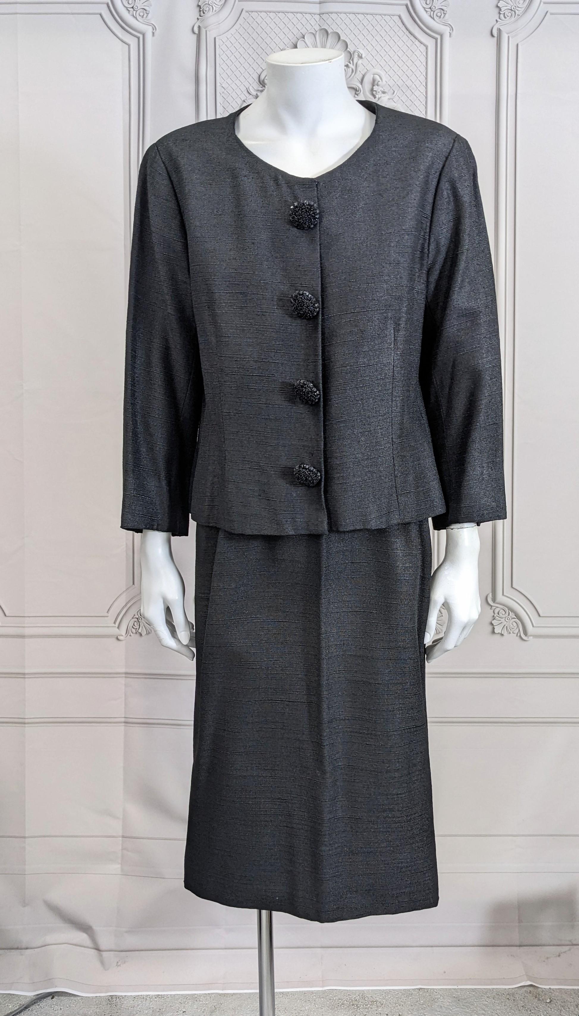 Elegant Cristobal Balenciaga Haute Couture Ribbed Silk Suit in an unusual black textile with slight sheen, likely of silk with wool. Deceptively simple cut with incredible hand made beaded buttons. Slim skirt with tiny side slits. Fully lined Jacket