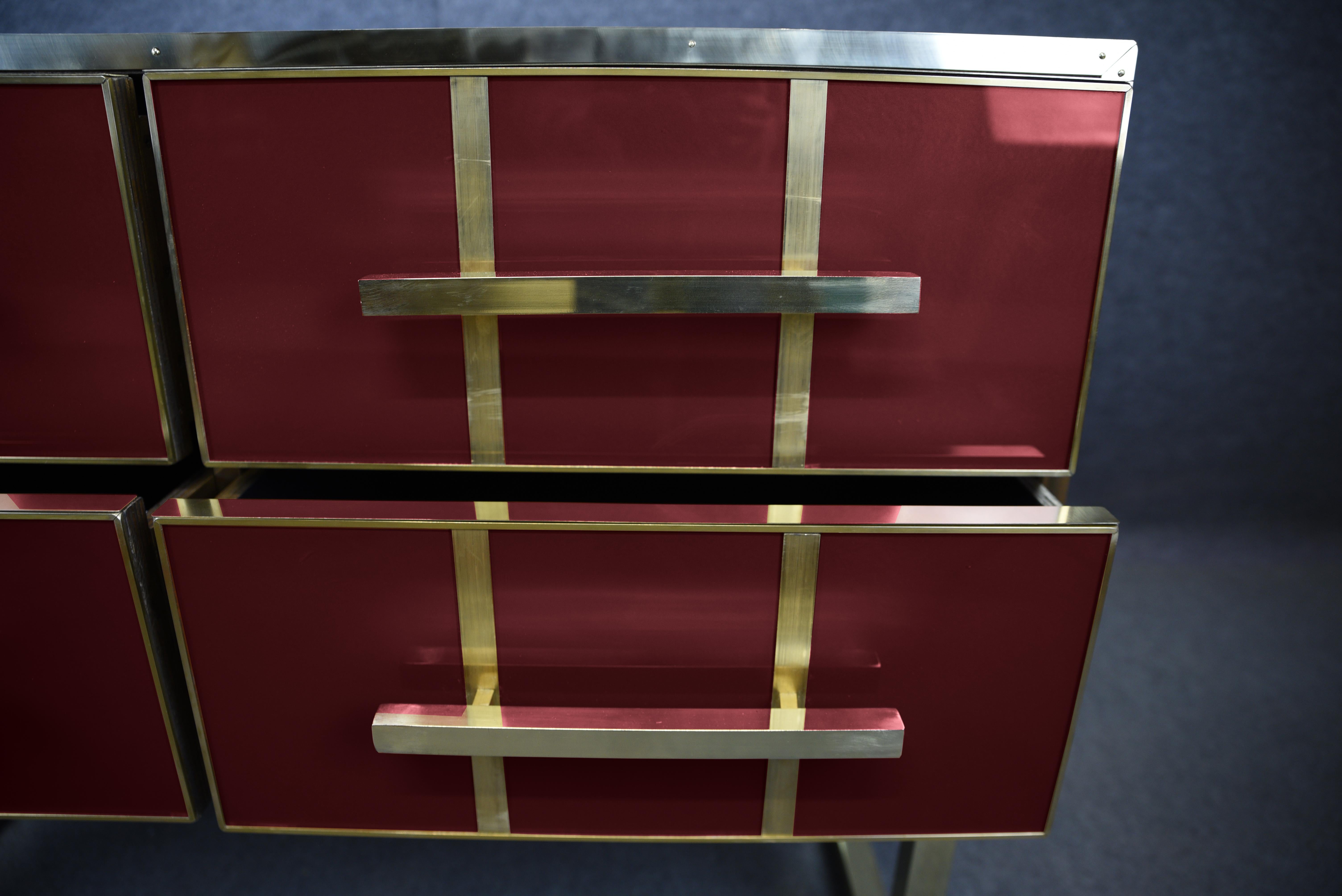 This exquisite Italian chest of drawers embodies mid-century modern elegance with a refined blend of solid wood, vibrant red Murano glass and polished brass fittings. 

Made in Italy, it features hand-painted details and is meticulously crafted by
