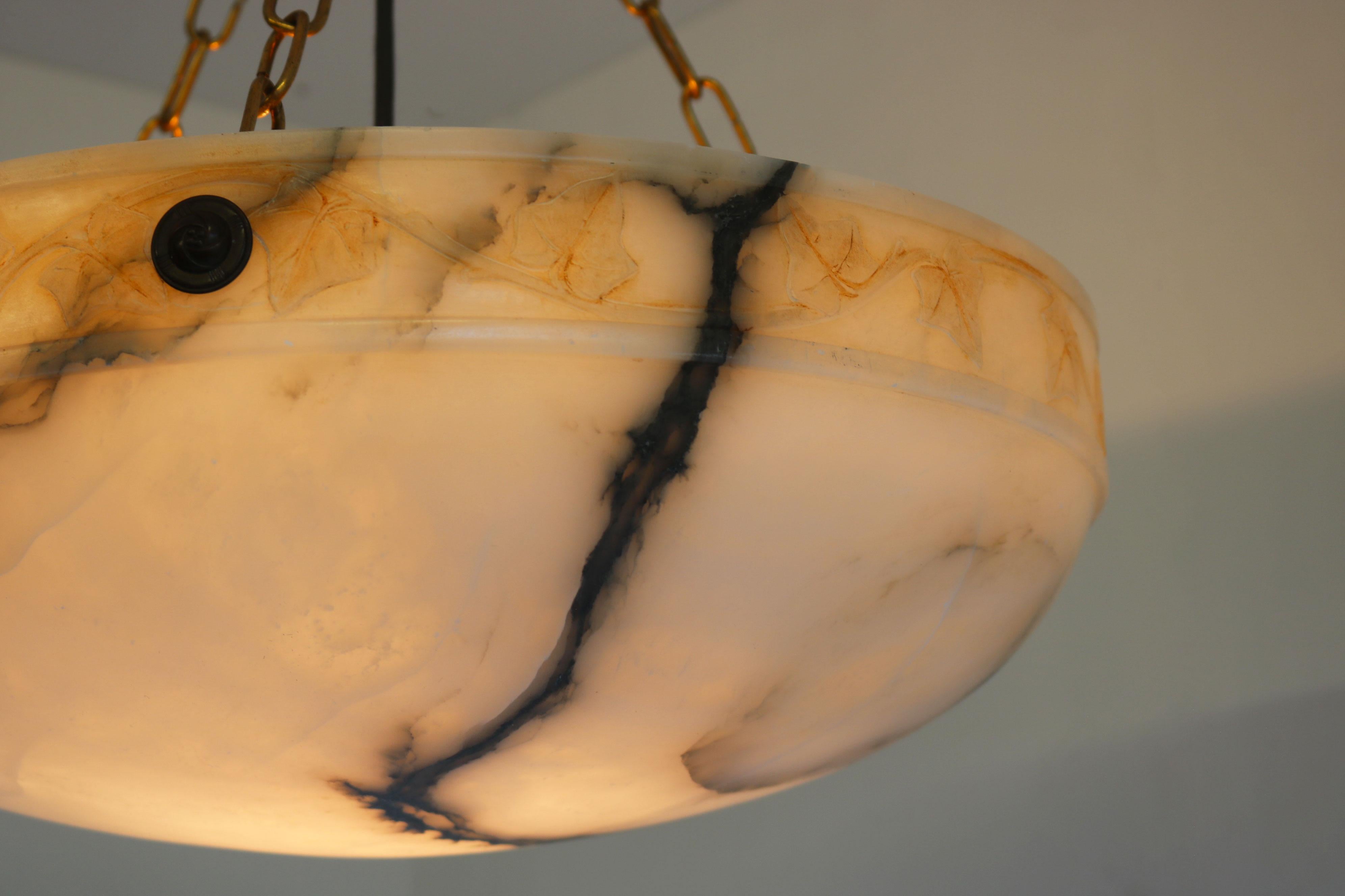 Raro lampadario in alabastro intagliato a mano in stile Art Carved con anello floreale e foglie. Direttamente dalla Francia, questo pezzo d'antiquariato senza tempo è semplicemente mozzafiato. 
Il paralume è stato ricavato da un unico blocco di