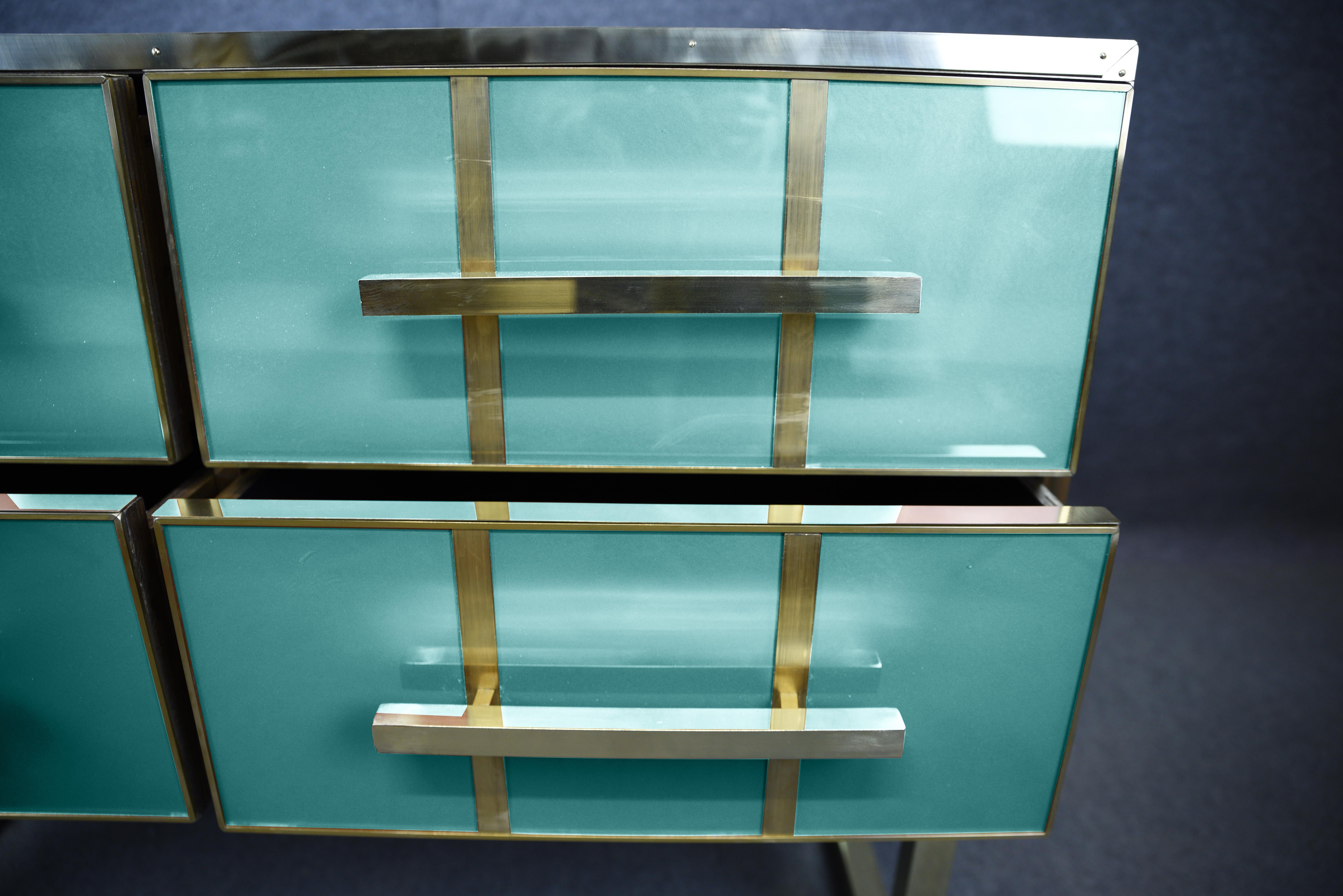 Esta cómoda italiana encarna el lujo atemporal, fusionando el estilo moderno de mediados de siglo con una sofisticada artesanía. 

Fabricado en madera maciza, presenta un exquisito cristal de Murano azul y detalles de latón pulido que le añaden un