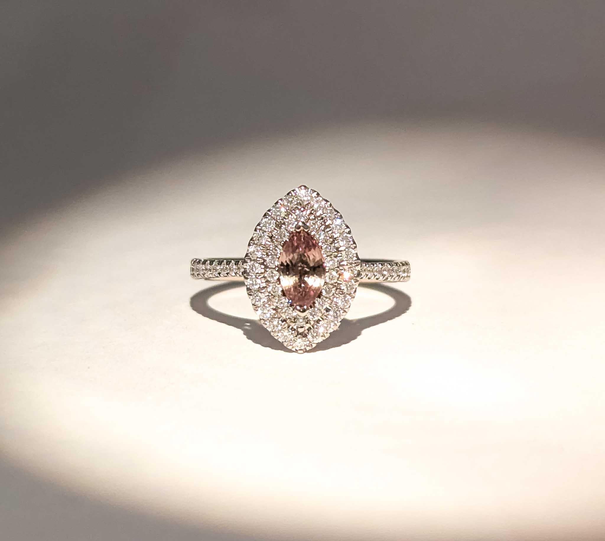 This exquisite ring showcases a captivating marquise-cut color-changing alexandrite, gracefully set within a double halo of dazzling diamonds. Crafted in lustrous 18k white gold, the design elegantly combines modern sophistication with a touch of