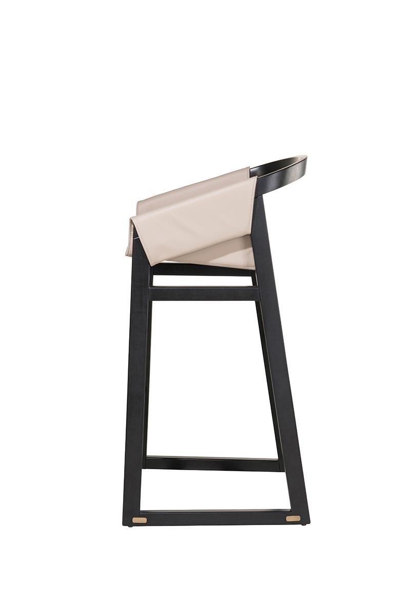 Der Barhocker Timeless ist ein raffiniertes Stück, das eine Massivholzkonstruktion mit einem eleganten Design kombiniert. Sein einzigartig geformter Sitz aus Naturleder verleiht ihm einen Hauch von Eleganz und Komfort. Die Fußstütze ist mit einem
