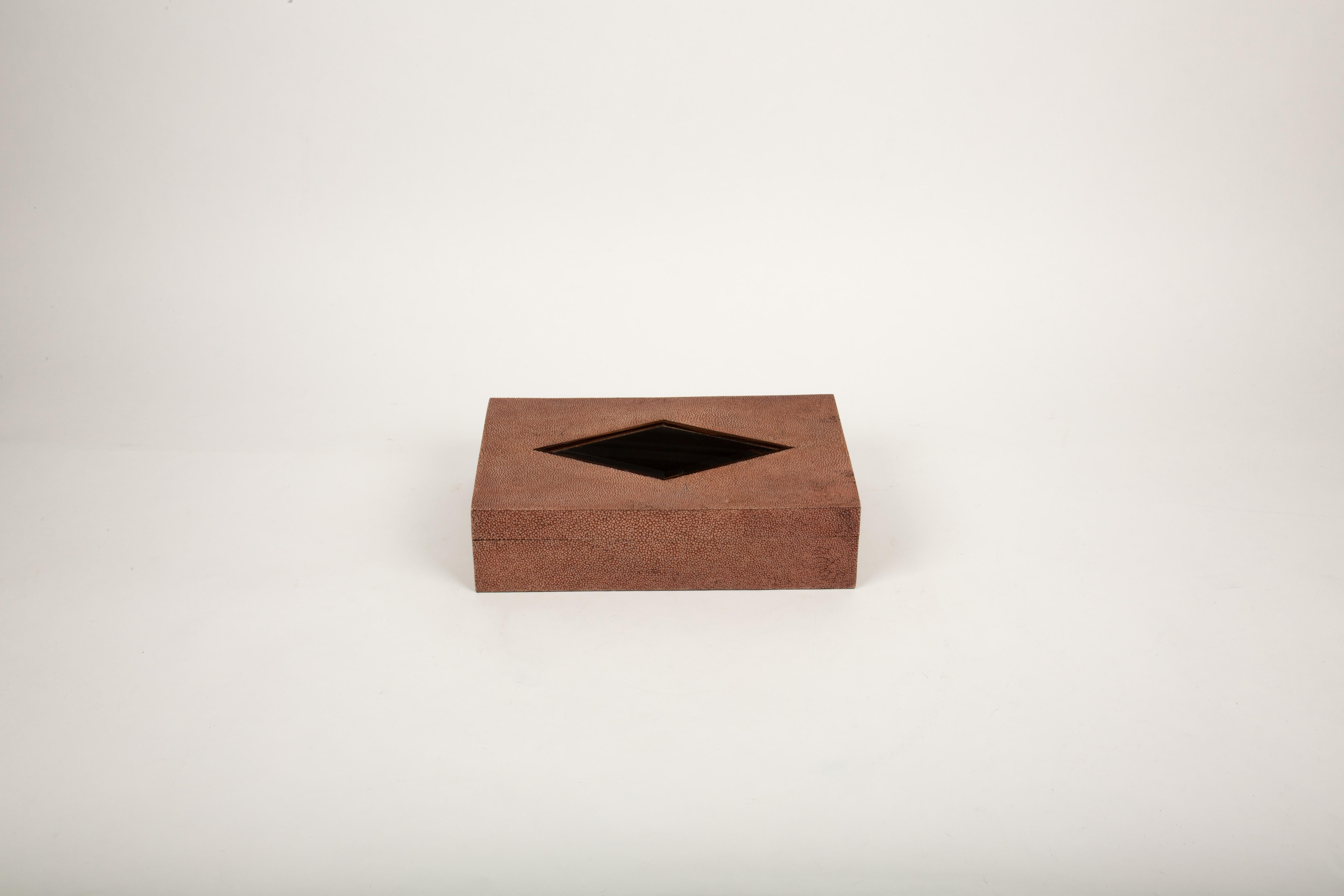 This luxurious brown shagreen box is a testament to exceptional craftsmanship, featuring a sleek diamond-shaped glass inset that adds a touch of sophistication. Measuring 6.5” x 9.75” x 2.5”H, it is handmade in the Philippines by master artisans