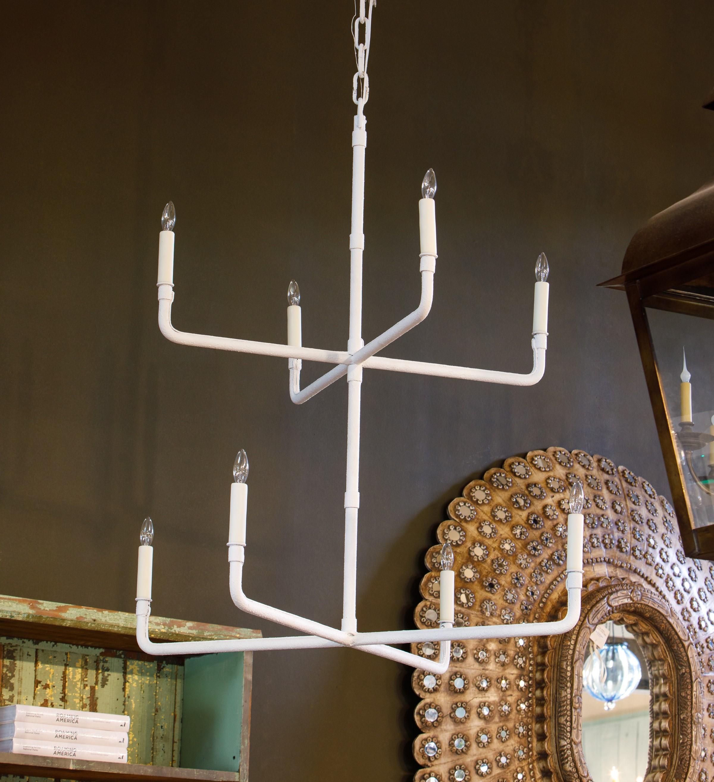 Two-tier hand-made iron chandelier of simple, minimalistic design. Eight alternating arms with candelabra-size sockets (each accommodates up to 60 watts). This particular version is painted white for sleek, more modern look; however, the light is