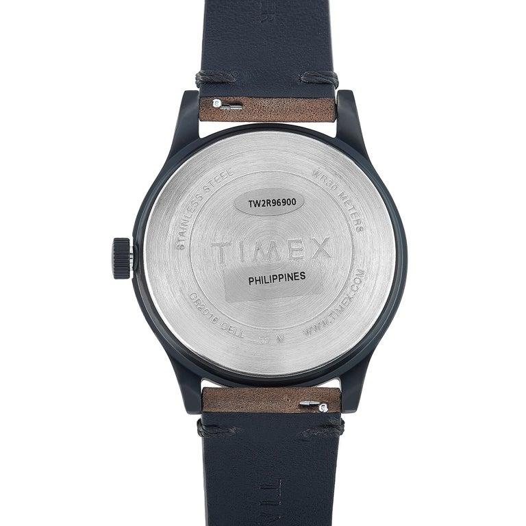Dies ist die Timex MK1 40 mm, Referenznummer TW2R96900. Die Uhr präsentiert sich mit einem schwarzen Edelstahlgehäuse mit einem Durchmesser von 40 mm. Das Gehäuse ist bis zu 30 Meter wasserdicht und wird an einem braunen Lederarmband mit
