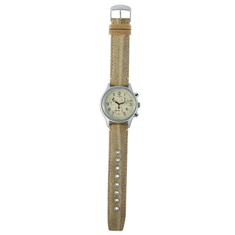This is the Timex MK1 Chronograph 42 mm watch, reference number TW2R68500. It is presented with a stainless steel case that offers water resistance of 50 meters. The case measures 42 mm in diameter and is mounted onto a beige khaki fabric strap,