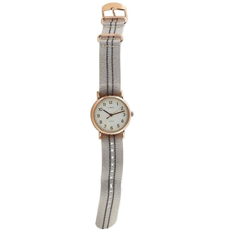 This is the Timex Weekender 38 mm, reference number TW2R92100. The watch is presented with a 38 mm rose gold-toned case that boasts stainless steel back. The case offers water resistance of 30 meters and is mounted onto a rose fabric strap, secured