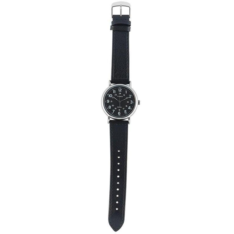 This is the Timex Weekender 40 mm, reference number TW2T30700. The watch is presented with a 40 mm silver-toned case that boasts stainless steel back. The case offers water resistance of 30 meters and is mounted onto a black leather strap, secured