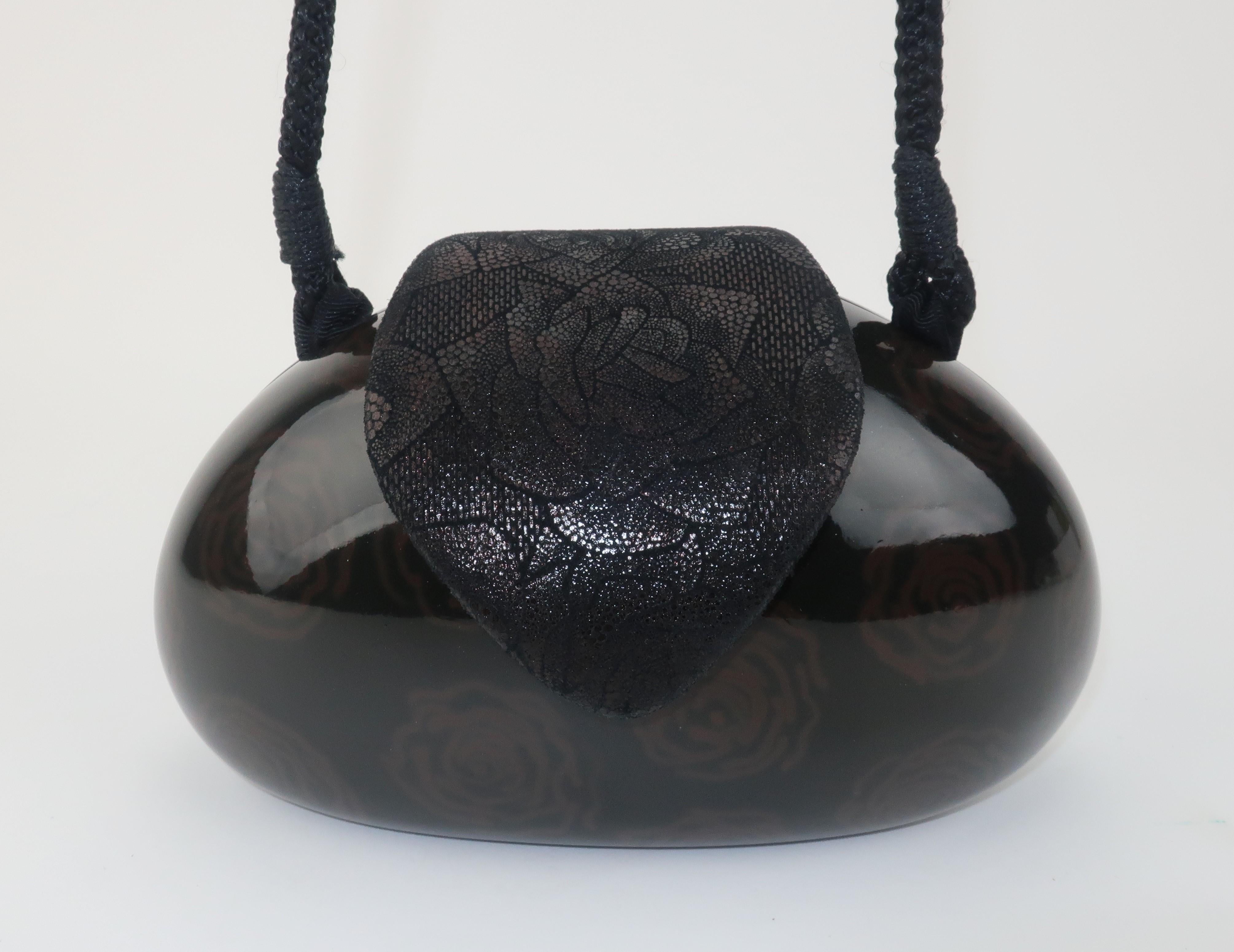 Witty ... whimsical ... wearable ... AND wooden!  This vintage Timmy Woods of Beverly Hills black lacquered wooden handbag has a capsule shape with a subtle brown floral pattern.  The unique snap top closure is a printed leather that combines a