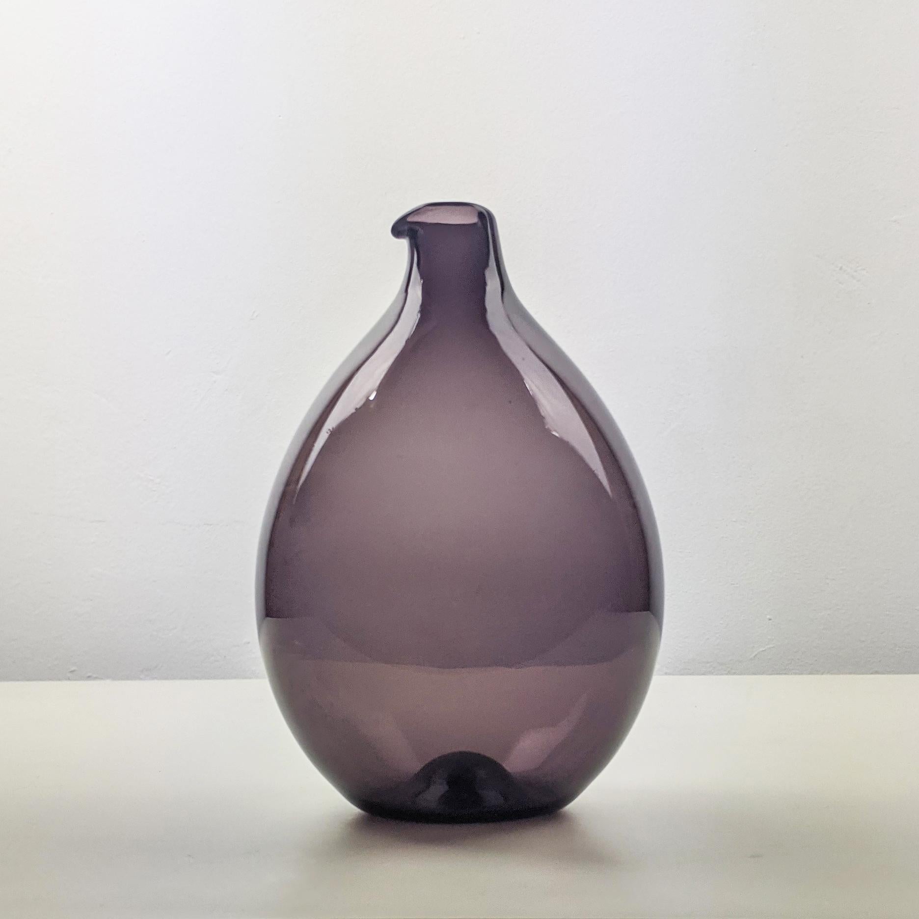 Timo Sarpaneva for Iittala, 1956.
Bird bottle (Lintupullo) ‘Round i-bottle’ from the i-line series.

Beautiful early example dating from 1957.
Purple-tinted clear blown glass.
Excellent condition.
Underside engraved 'Timo Sarpaneva, Iittala,