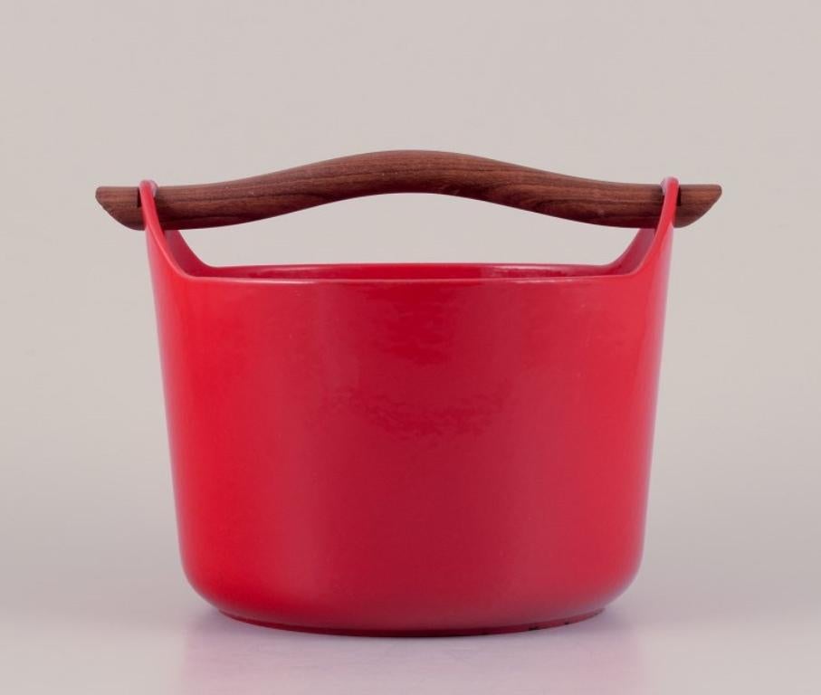 Timo Sarpaneva for Rosenlew, Finland. 
Cast iron pot in red enamel with a wooden handle.
From the 1960s/70s.
Marked.
In good condition with a small chip in the enamel on the top of the handle. See photo.
Dimensions: H 18.0 cm x 22.5 cm without the