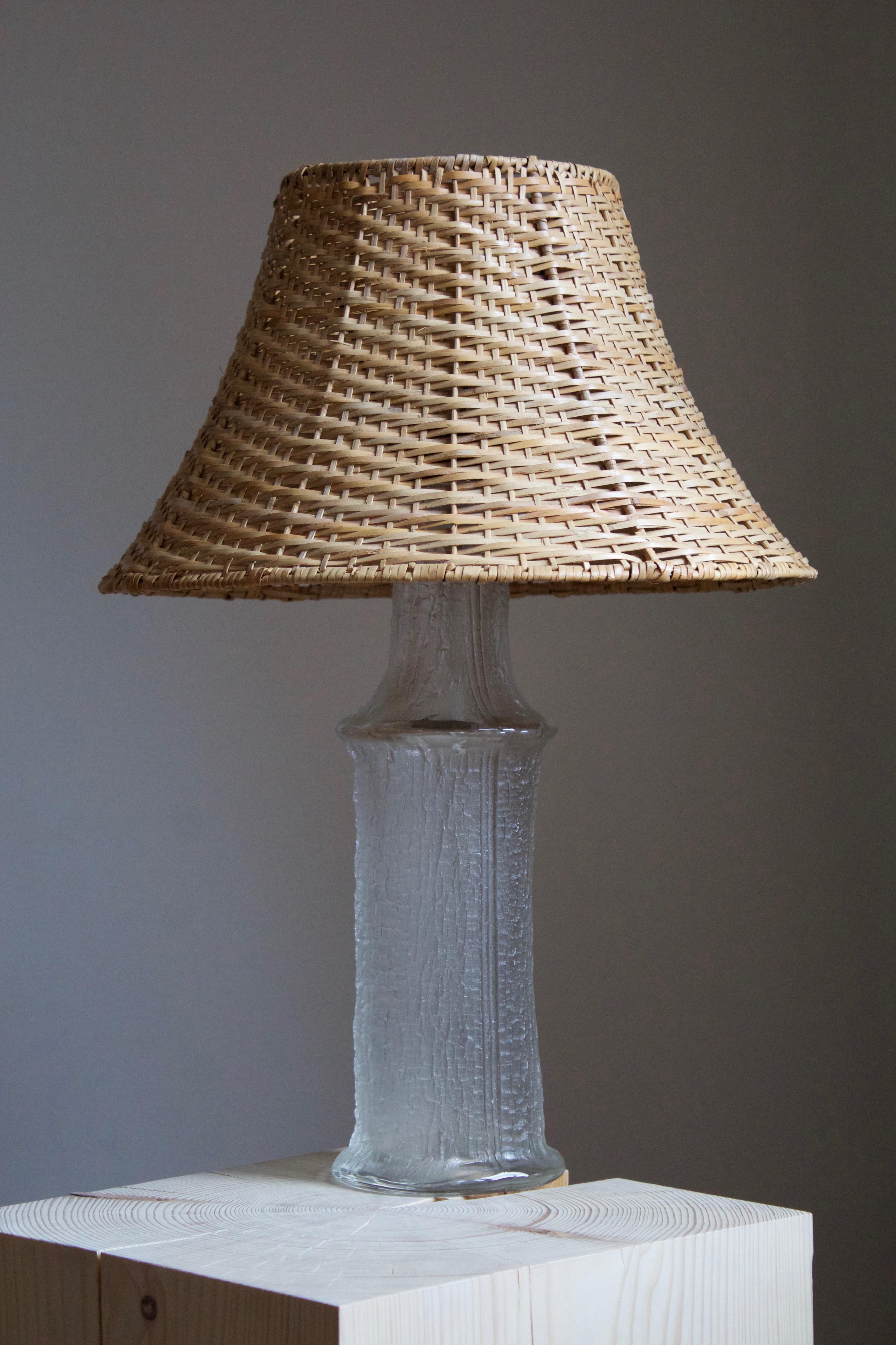 A table lamp, designed by Timo Sarpaneva. Glass produced by Finnish glass maker Ittala for Swedish firm Lilux Belysning Ab. With an assorted vintage rattan lampshade.