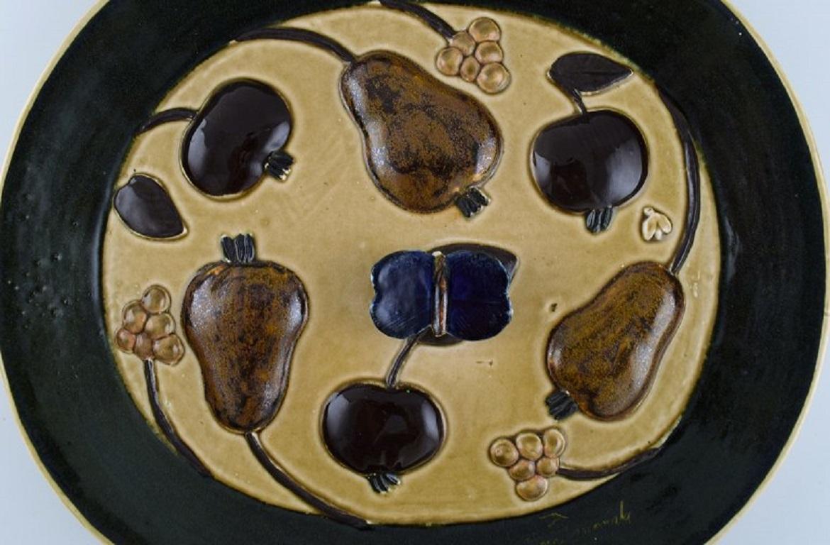 Timo Sarvimäki (né en 1948) pour Designhuset. Plat ovale en céramique émaillée avec fruits et papillon en relief. 
Design finlandais, années 1970.
Mesures : 34 x 30 x 3,8 cm.
En parfait état.
Signé.