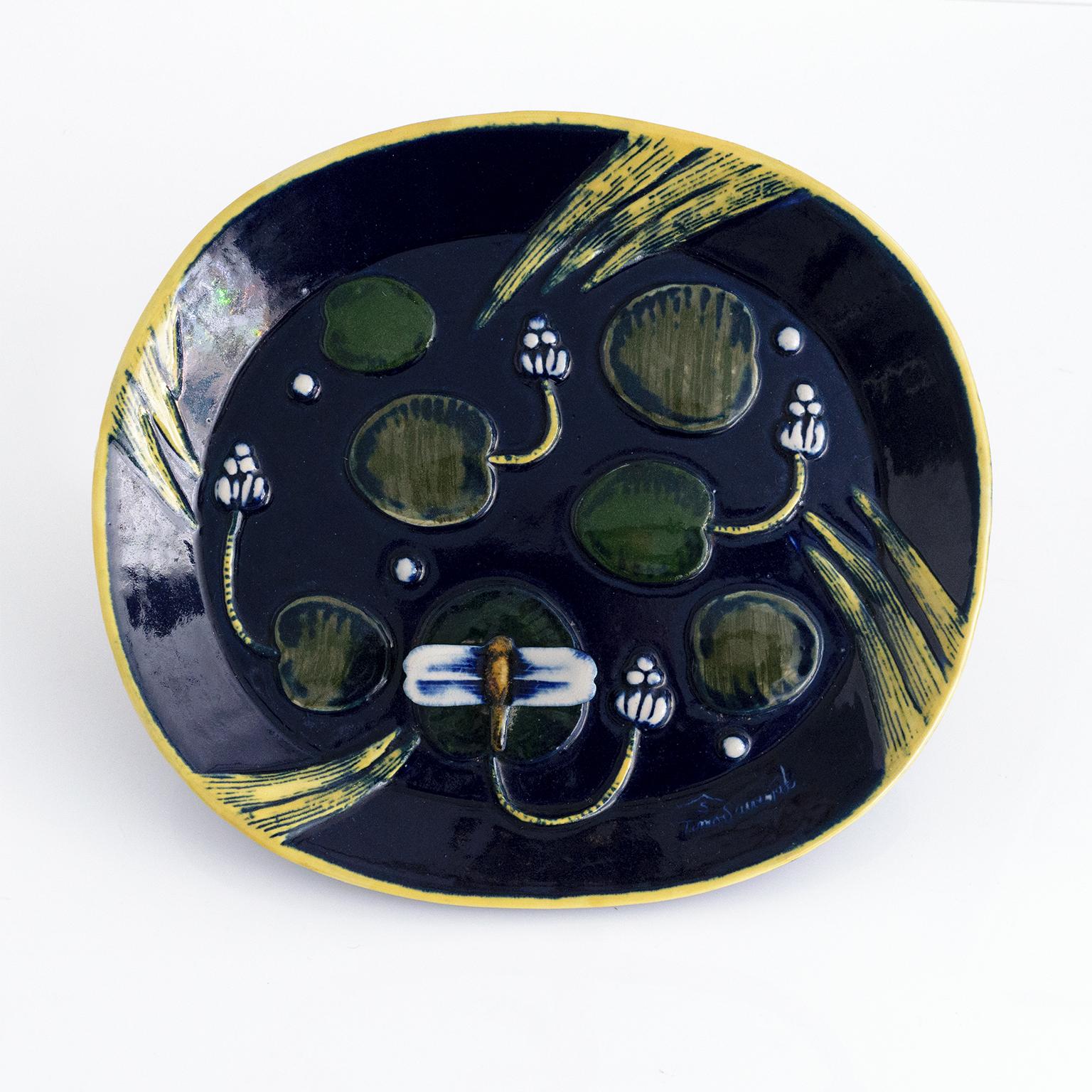 Timo Sarvimäki stoneware platter depicting a deep blue pond or lake surface with lily pads, and a dragon fly in relief. Produced for Designhuset, Stockholm 1960's. 

Measures: Length: 13.5” Width: 12“ Height: 1.5.